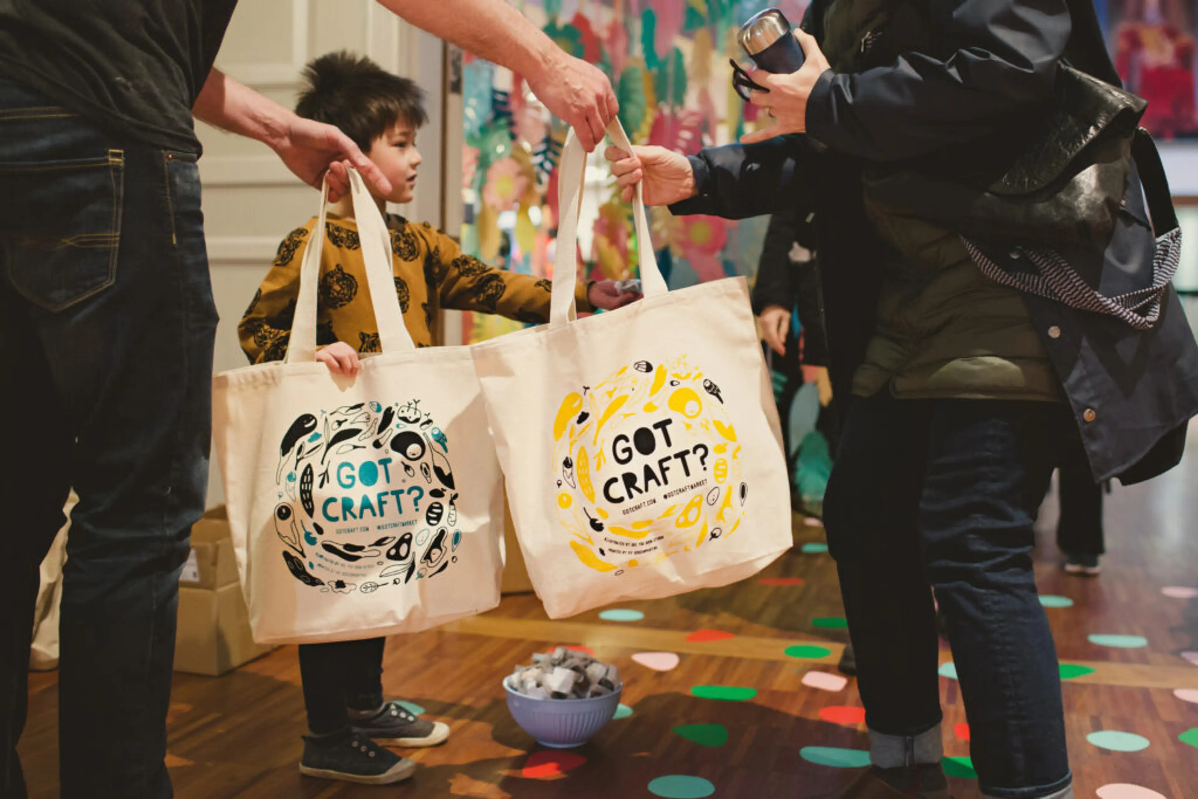 A person passes out cloth tote bags full of swag at Got Craft