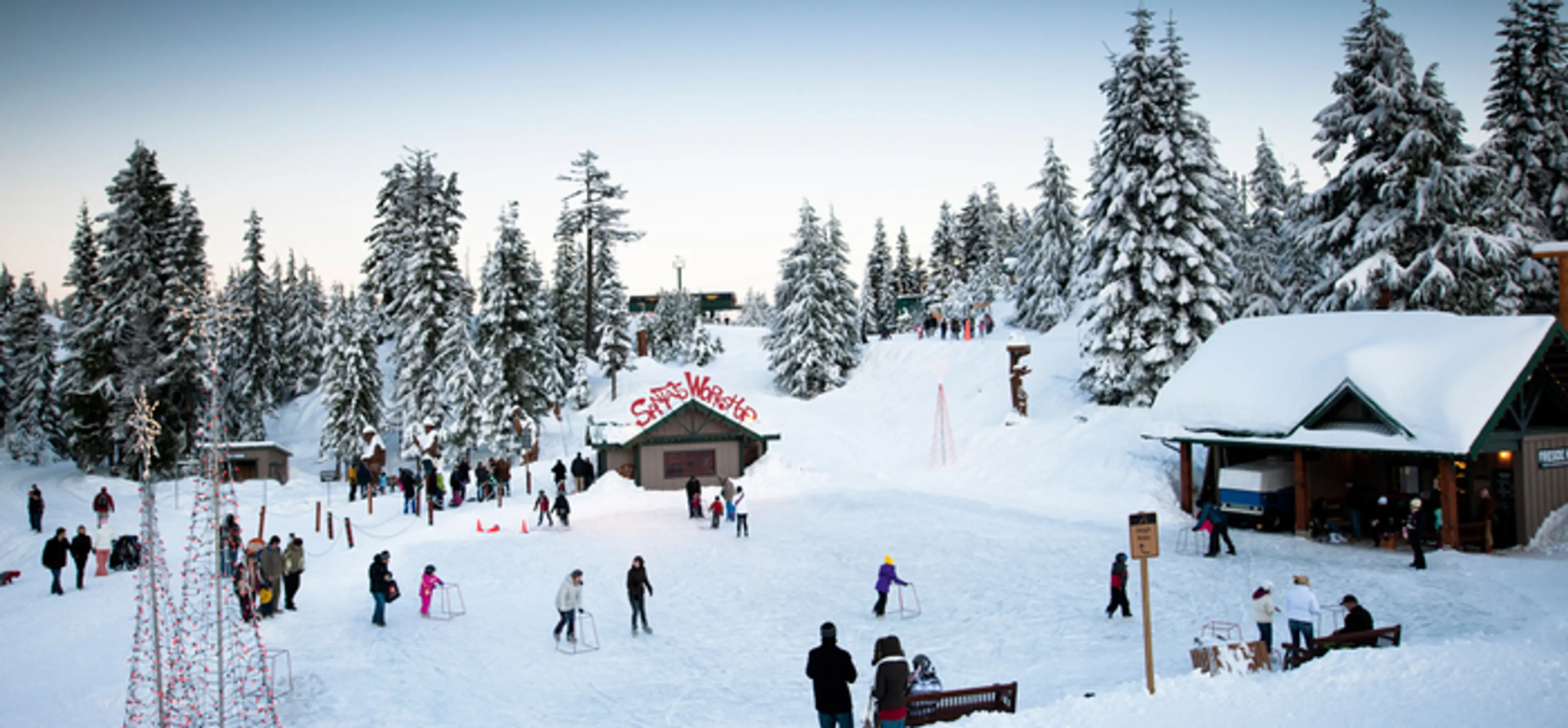 Skaters on the mountaintop pond at Grouse Mountain surrounded by snow. 