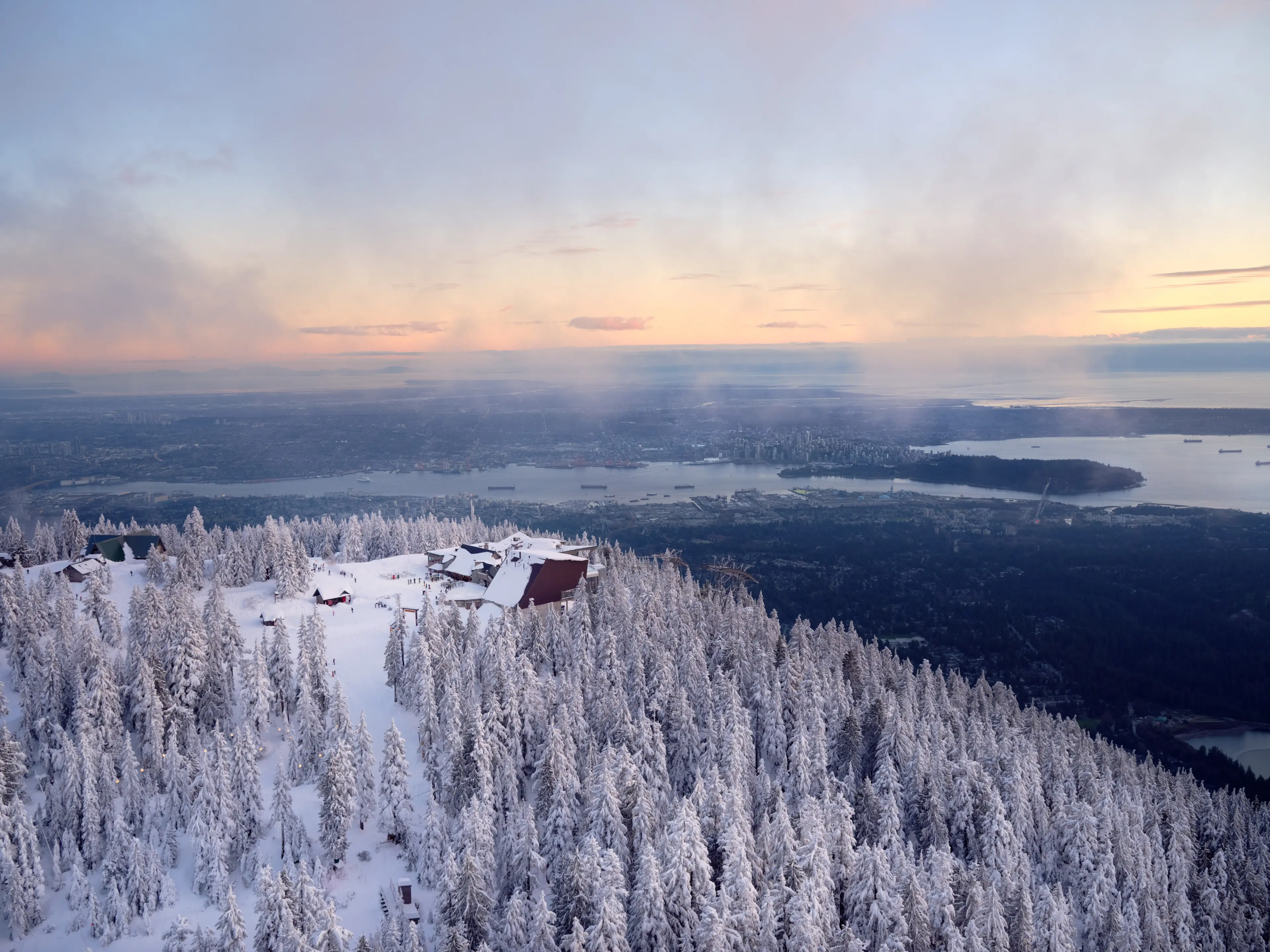 An aerial view of Grouse Mountain in winter with the city in the background. 