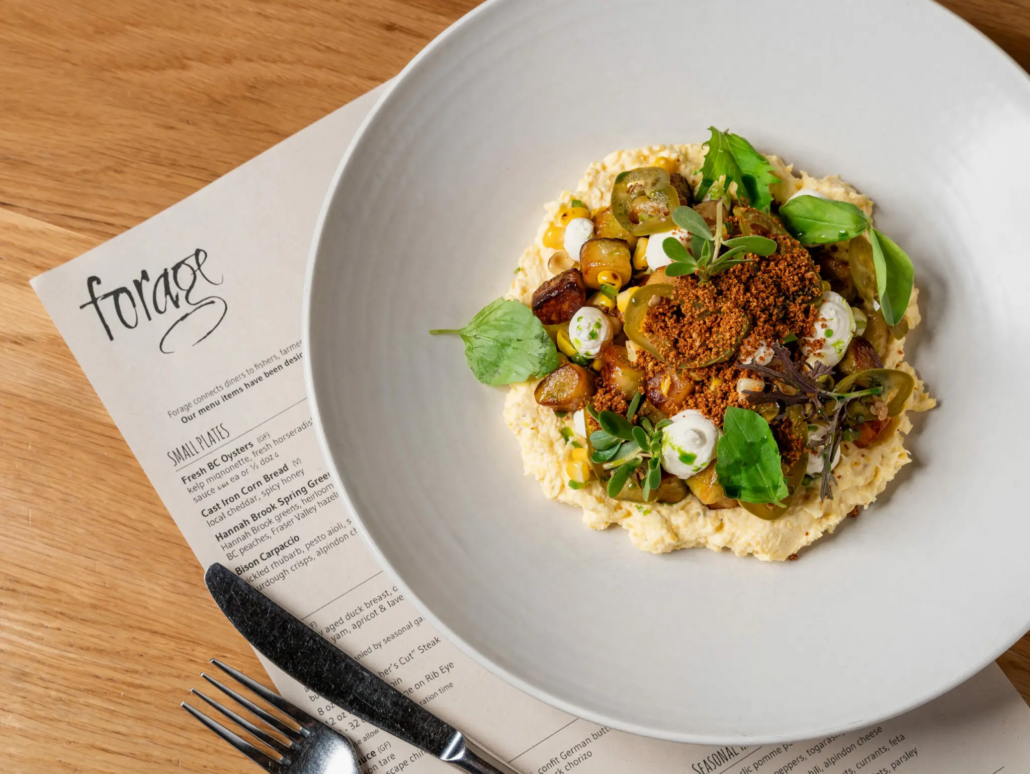 A plate of food sits atop a menu at Forage restaurant in Vancouver