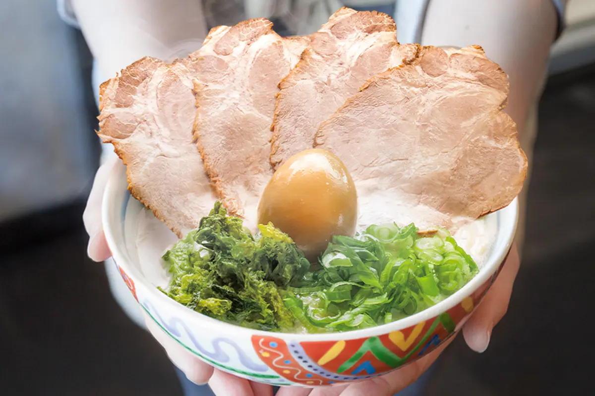 Hands holding a bowl of cashu tamago ramen at Maruhachi Ra-men