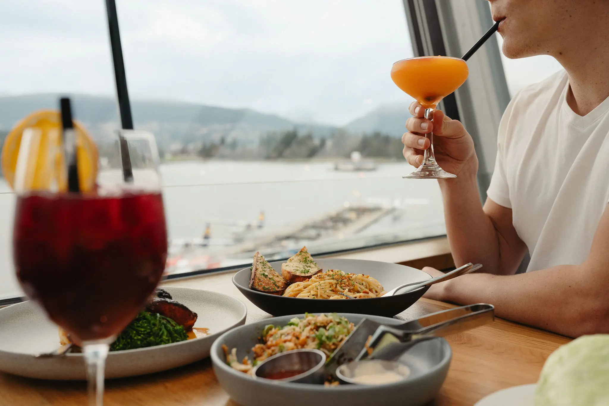 A person holding a drink at the window seat lookingout to Coal Harbour at Cactus Club in Vancouver.