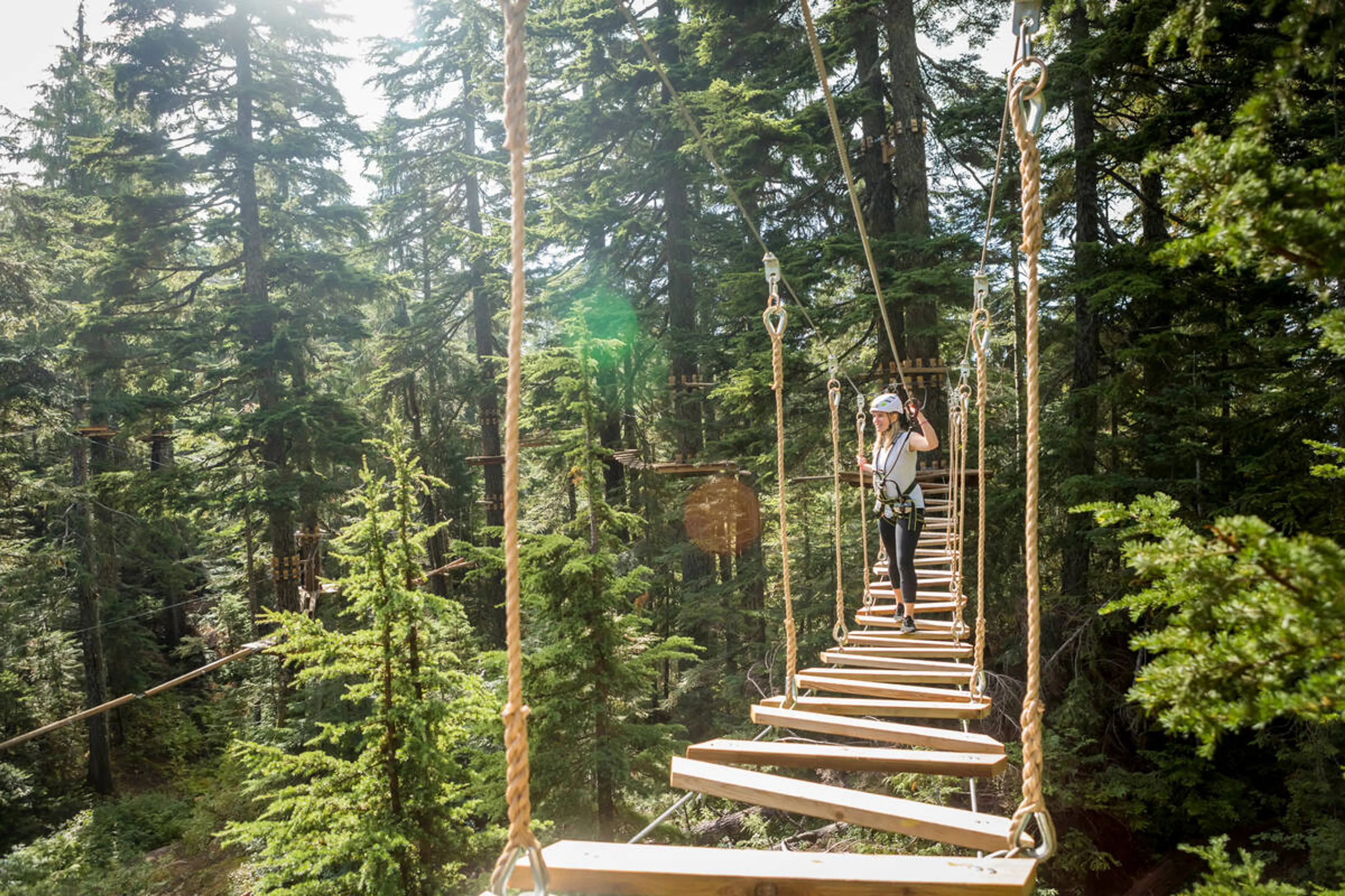 A person crosses a plank bridge on a ropes course at Grouse Mountain.