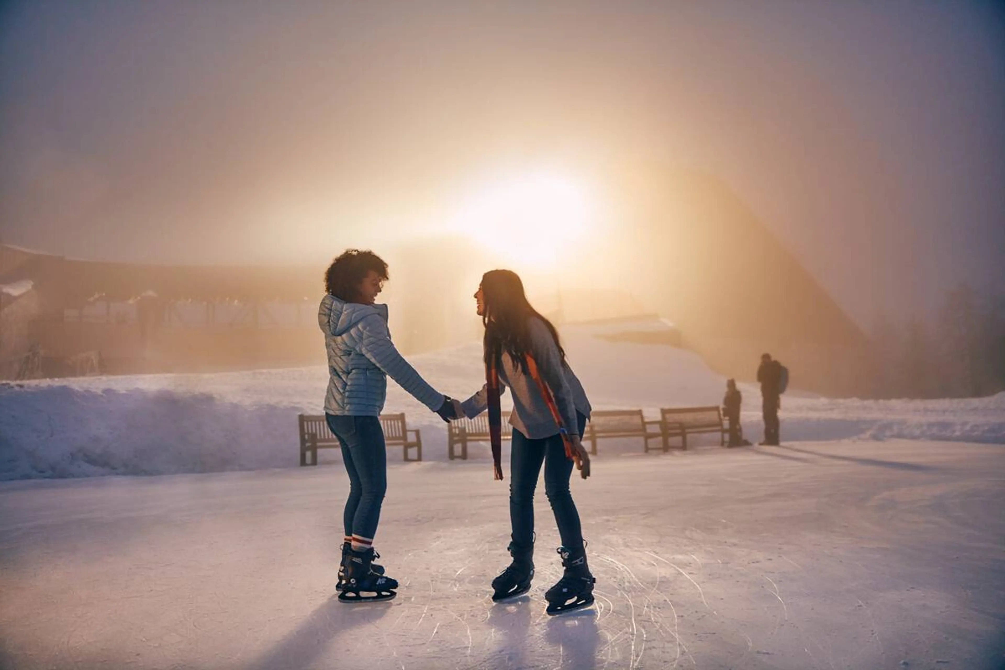Two womens skating on the mountain top skating pond at Grouse Mountain. 