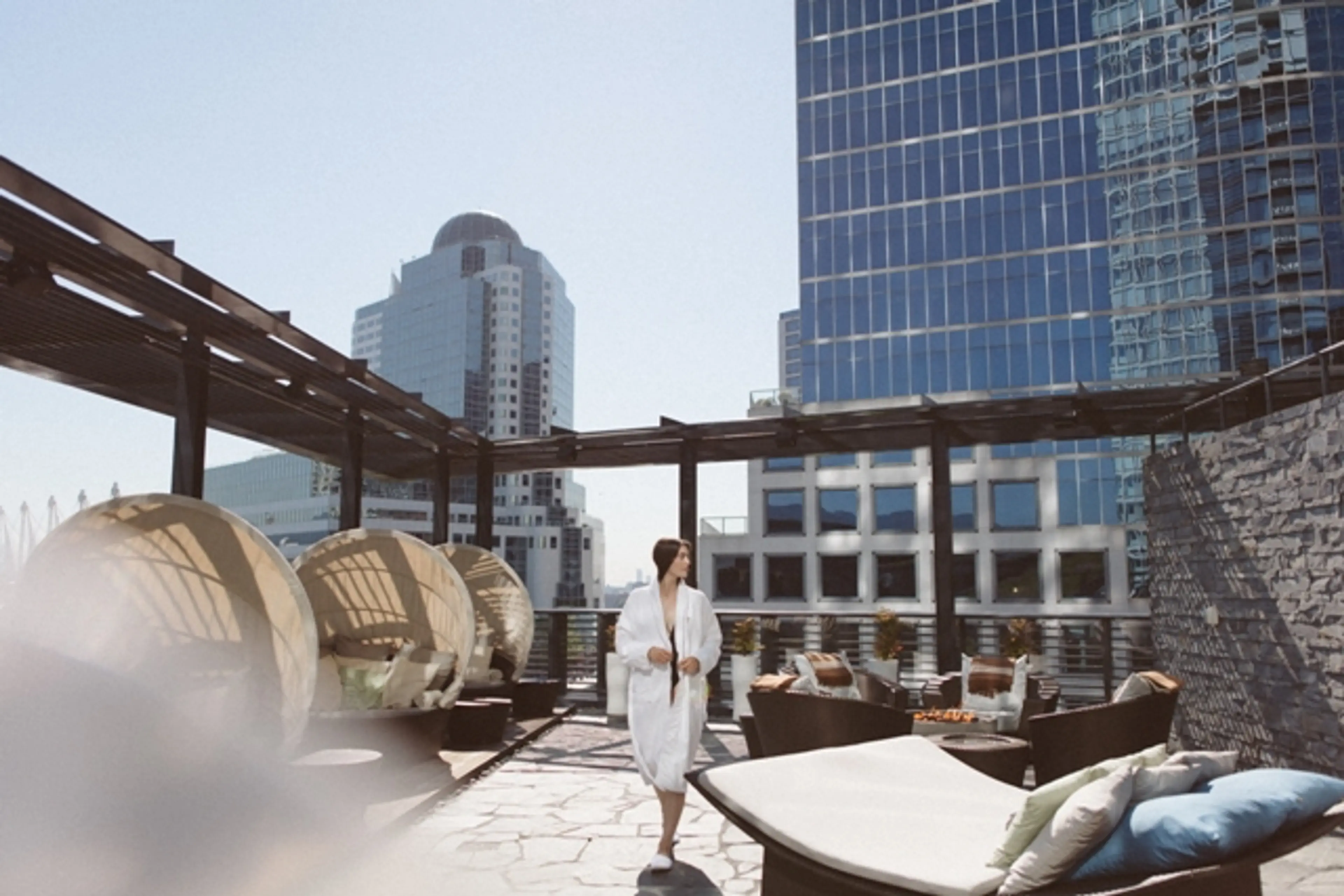 A woman in a bathrobe walks along the outdoor terrace at the spa at the Fairmont Pacific Rim. 