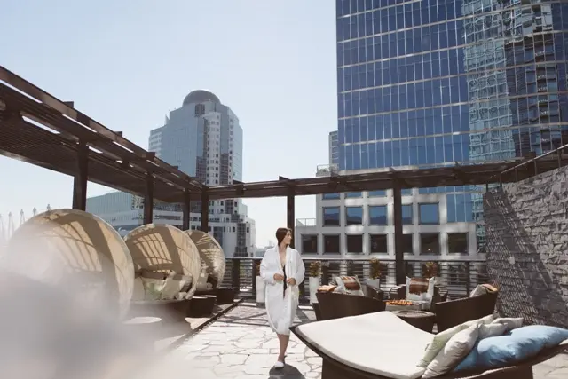 A woman in a bathrobe walks along the outdoor terrace at the spa at the Fairmont Pacific Rim.