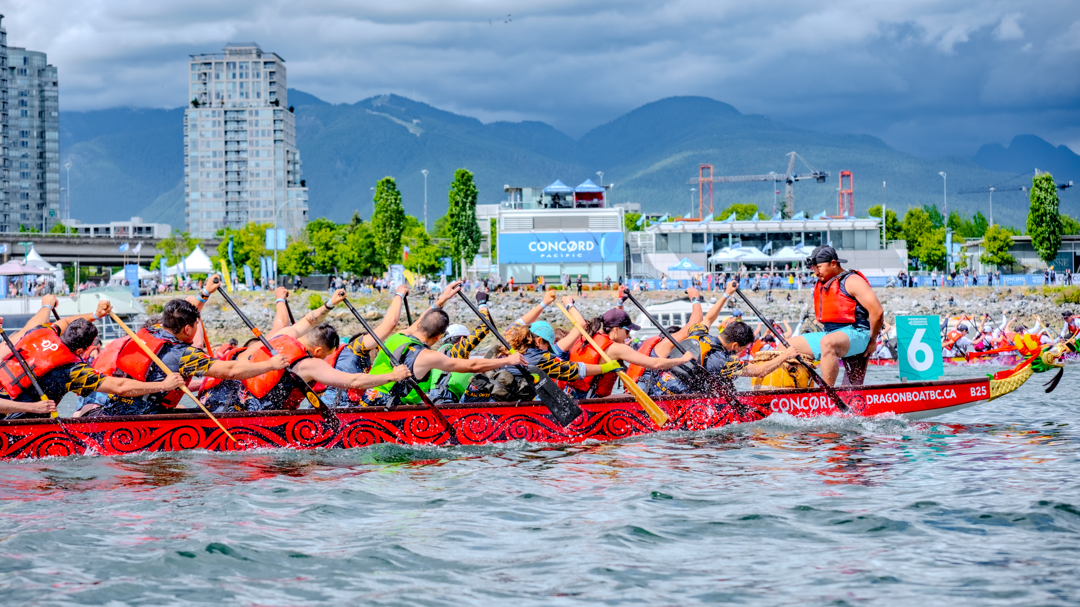 Paddlers race in the Concord Pacific Dragon Boat Festival with local mountains in the background