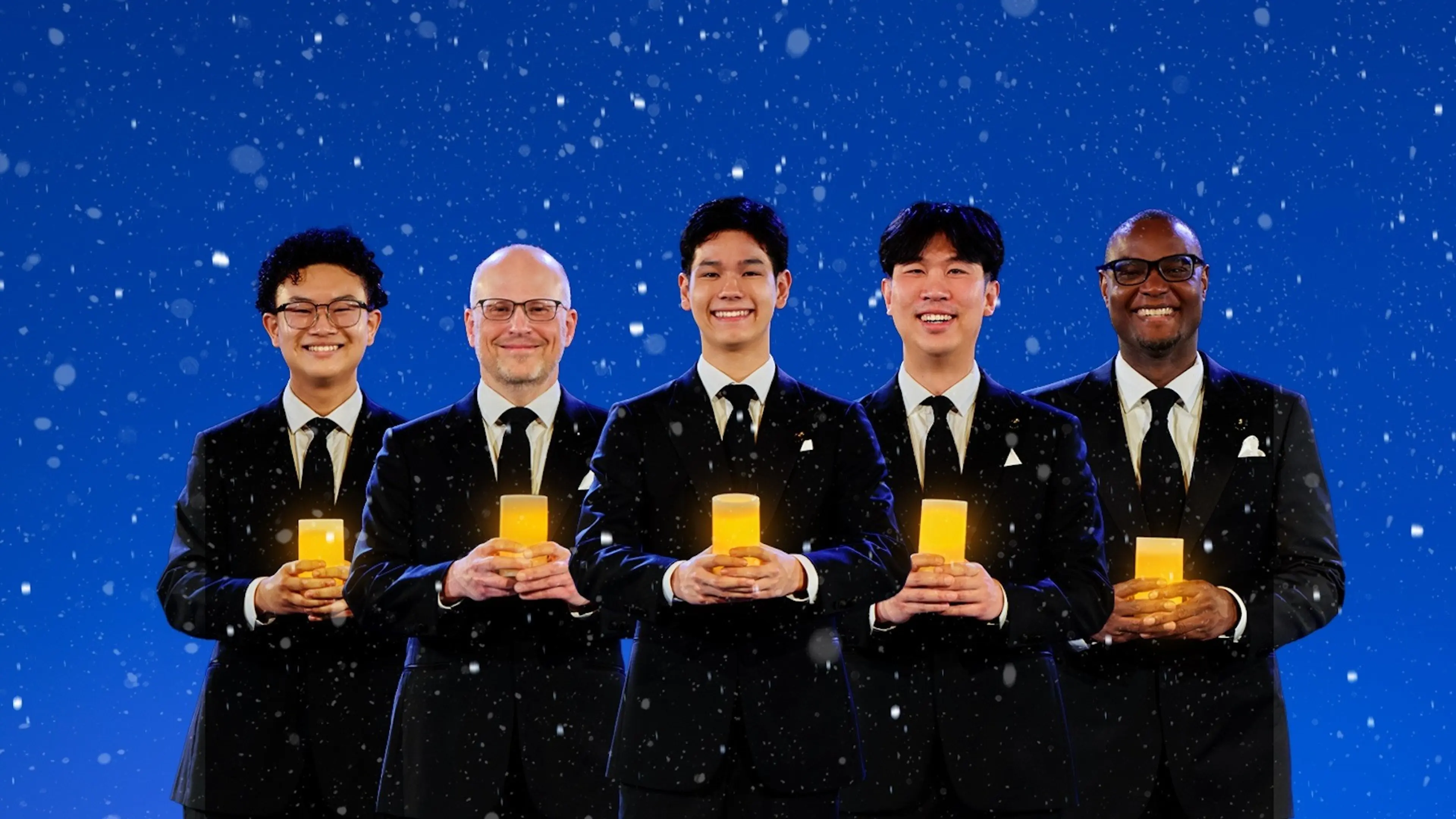 Five people in black suits holding glowing candles against a blue background with falling snow.