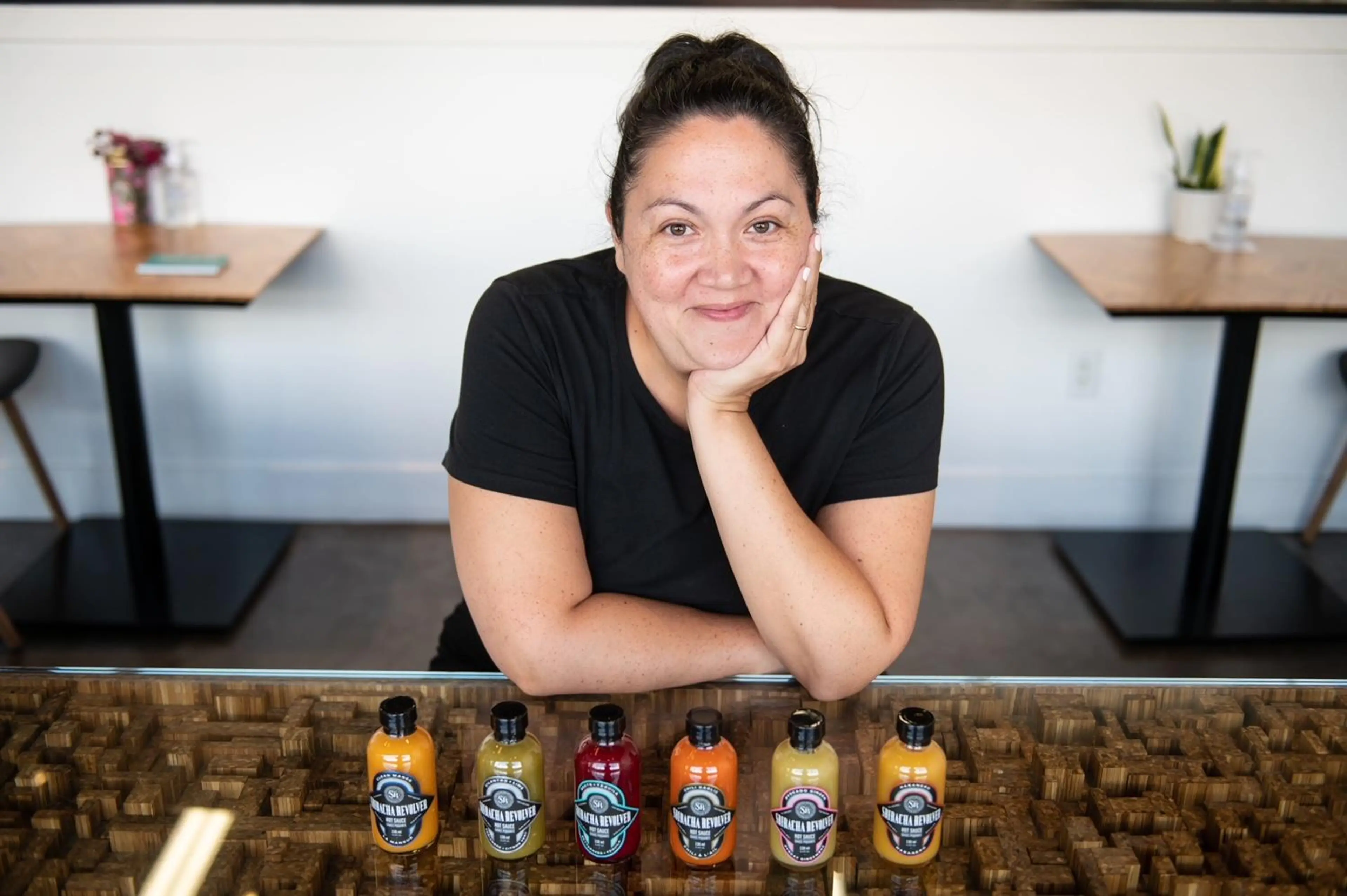Jordan Hocking of Sriracha Revolver poses behind her hot sauces