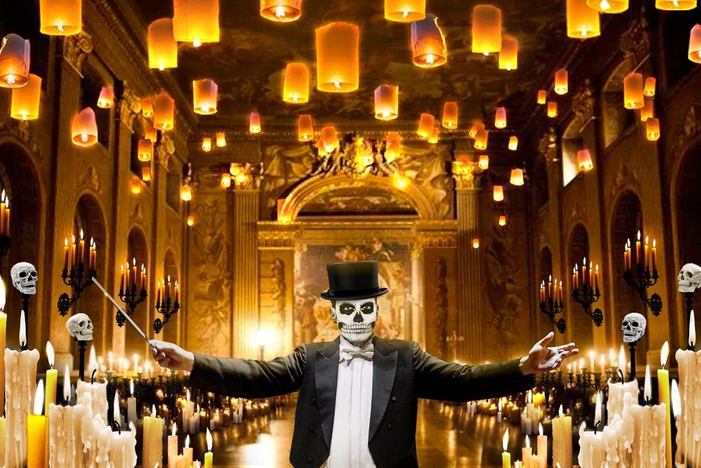 Person in a tuxedo and top hat with skull face paint conducting in a candlelit hall with floating lanterns and skull decorations.