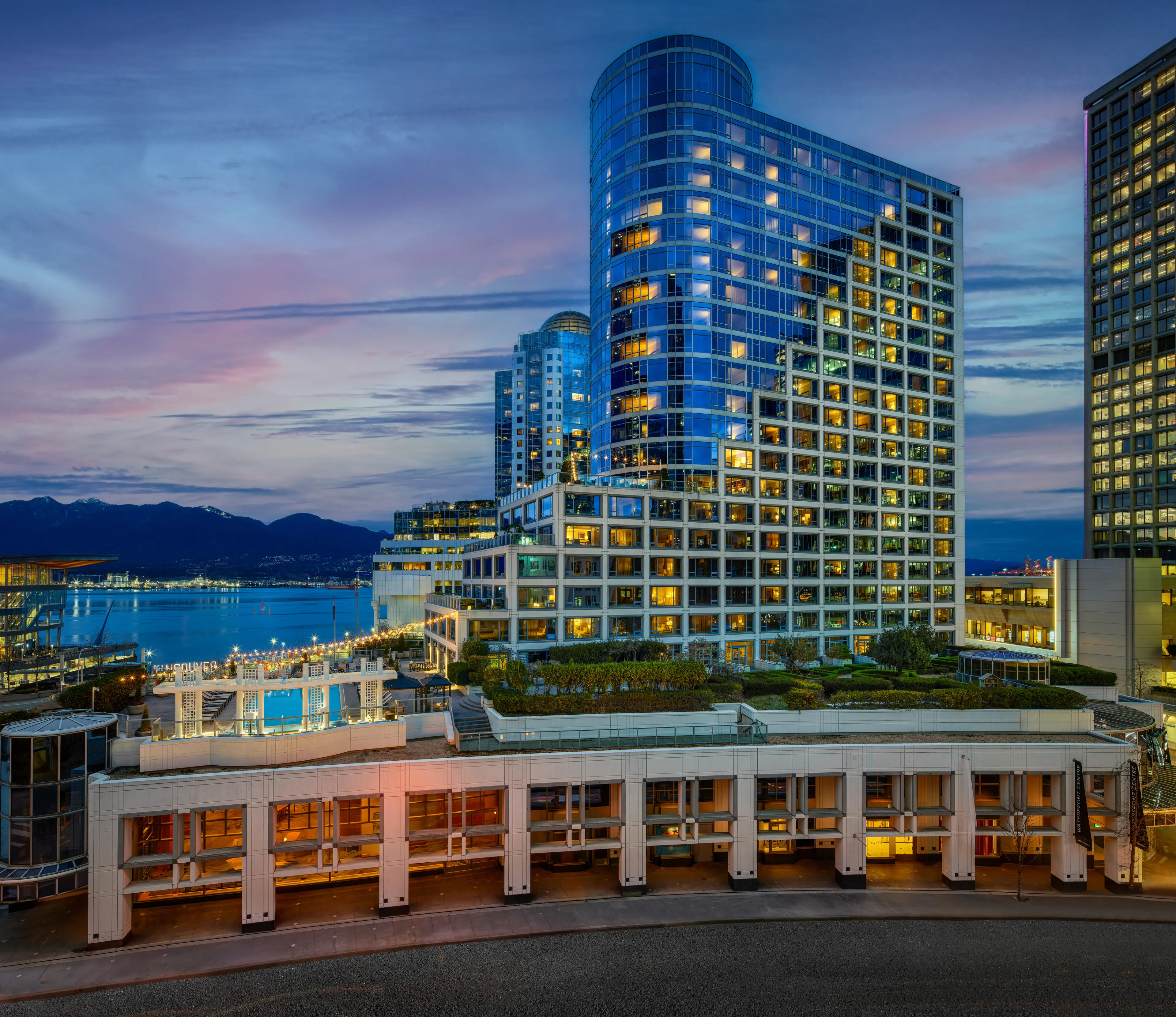 The exterior of the Fairmont Waterfront hotel with mountains and water in the background