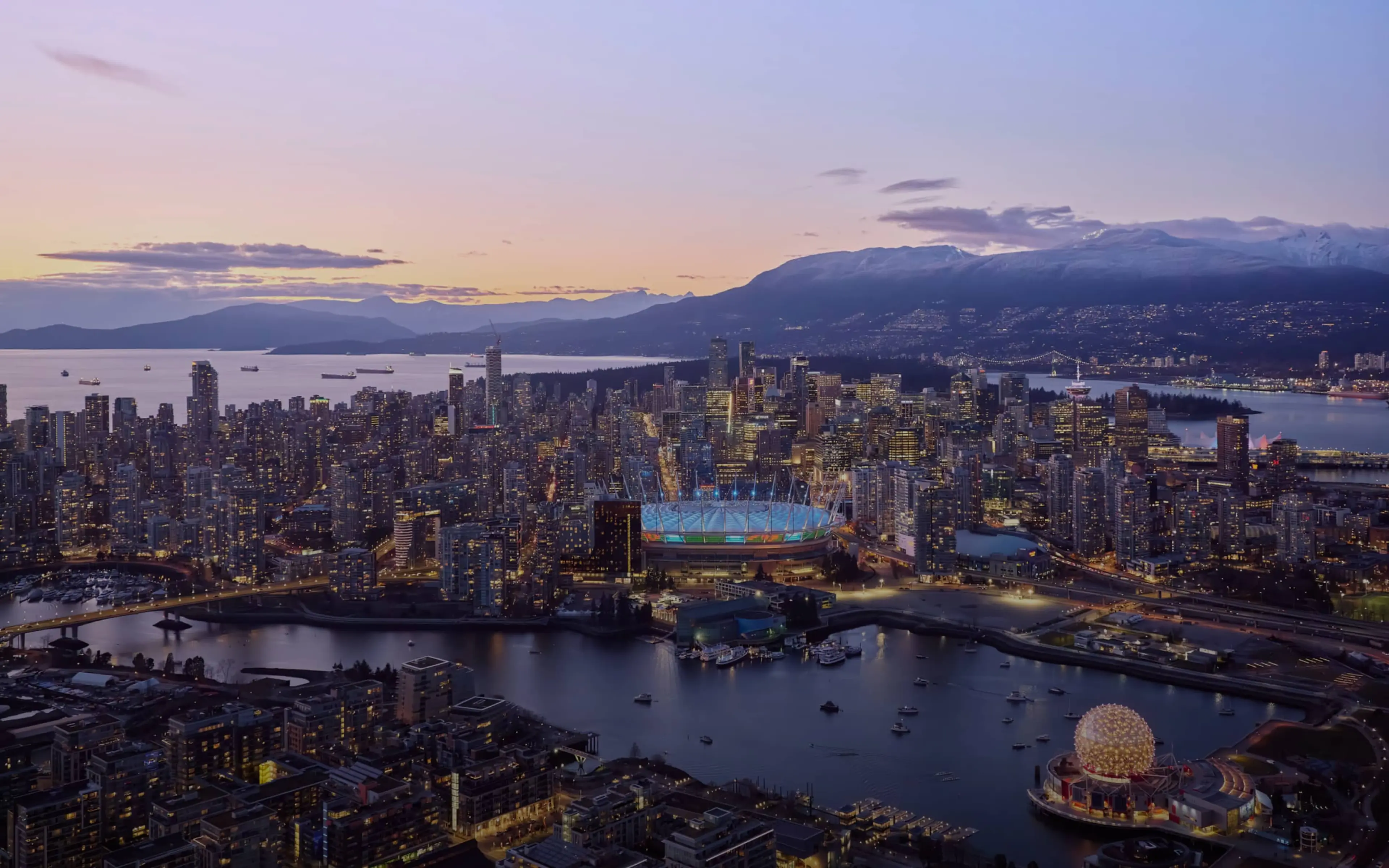 An arial shot of Vancouver shows BC Place on one side of the water and Science World on the other.