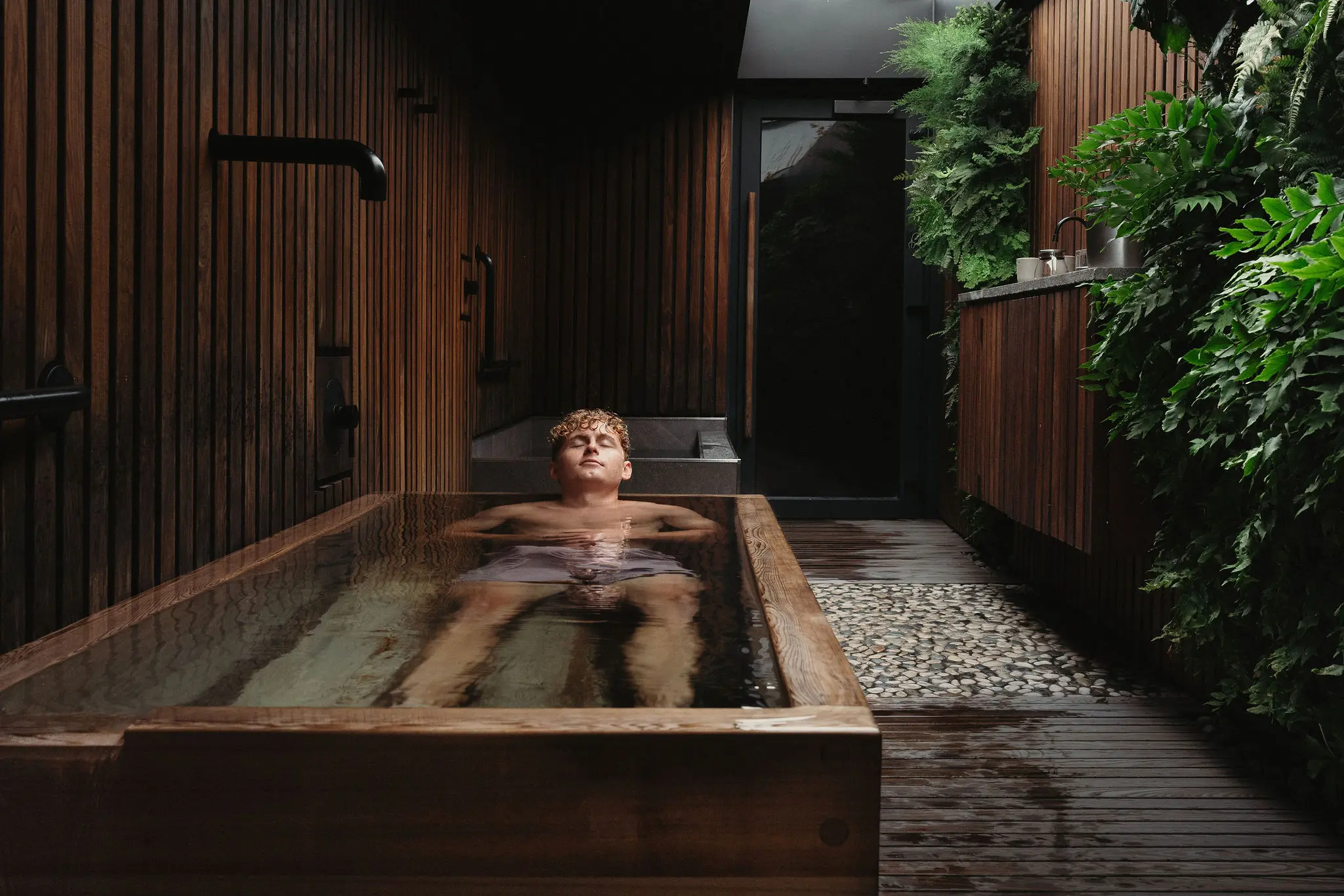A person enjoying a bath in a wooden bathtub at Circle Wellness, Vancouver.
