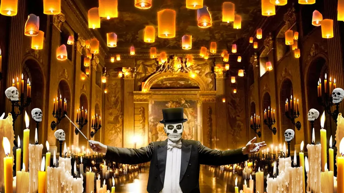 Person in skeleton face paint and top hat conducting in a grand hall with floating lanterns, candles, and skull decorations.