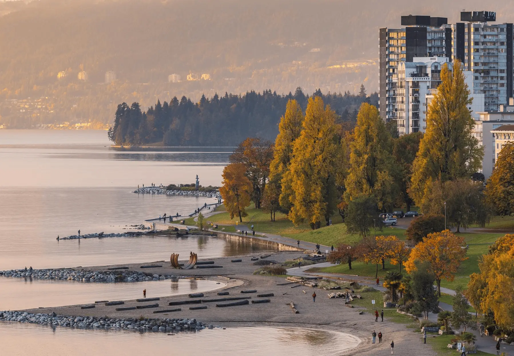 The coast of Vancouver at sunset. Curved sandy beaches with grass, trees and buildings behind.