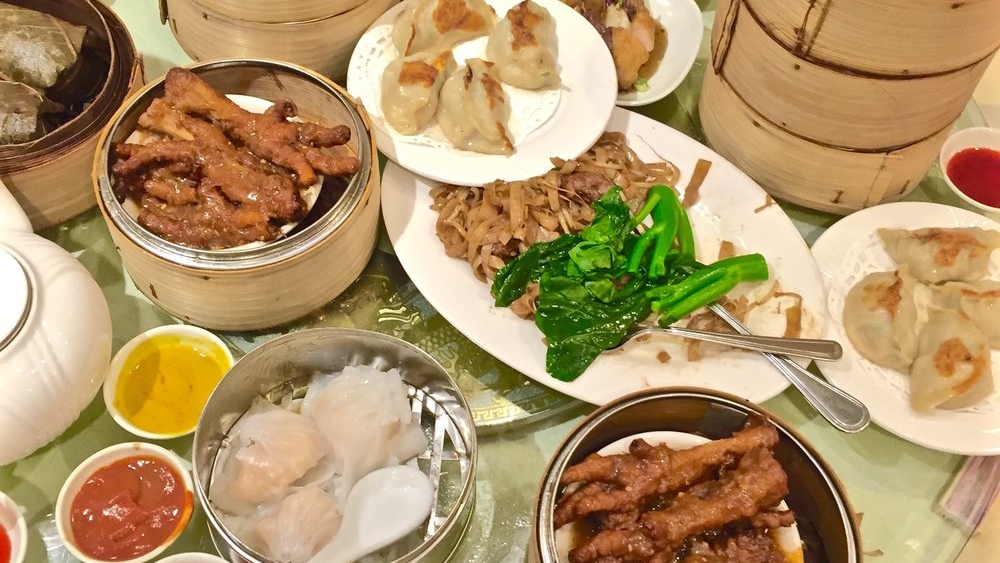 A table covered in dim sum dishes in bamboo steamer baskets and on plates.