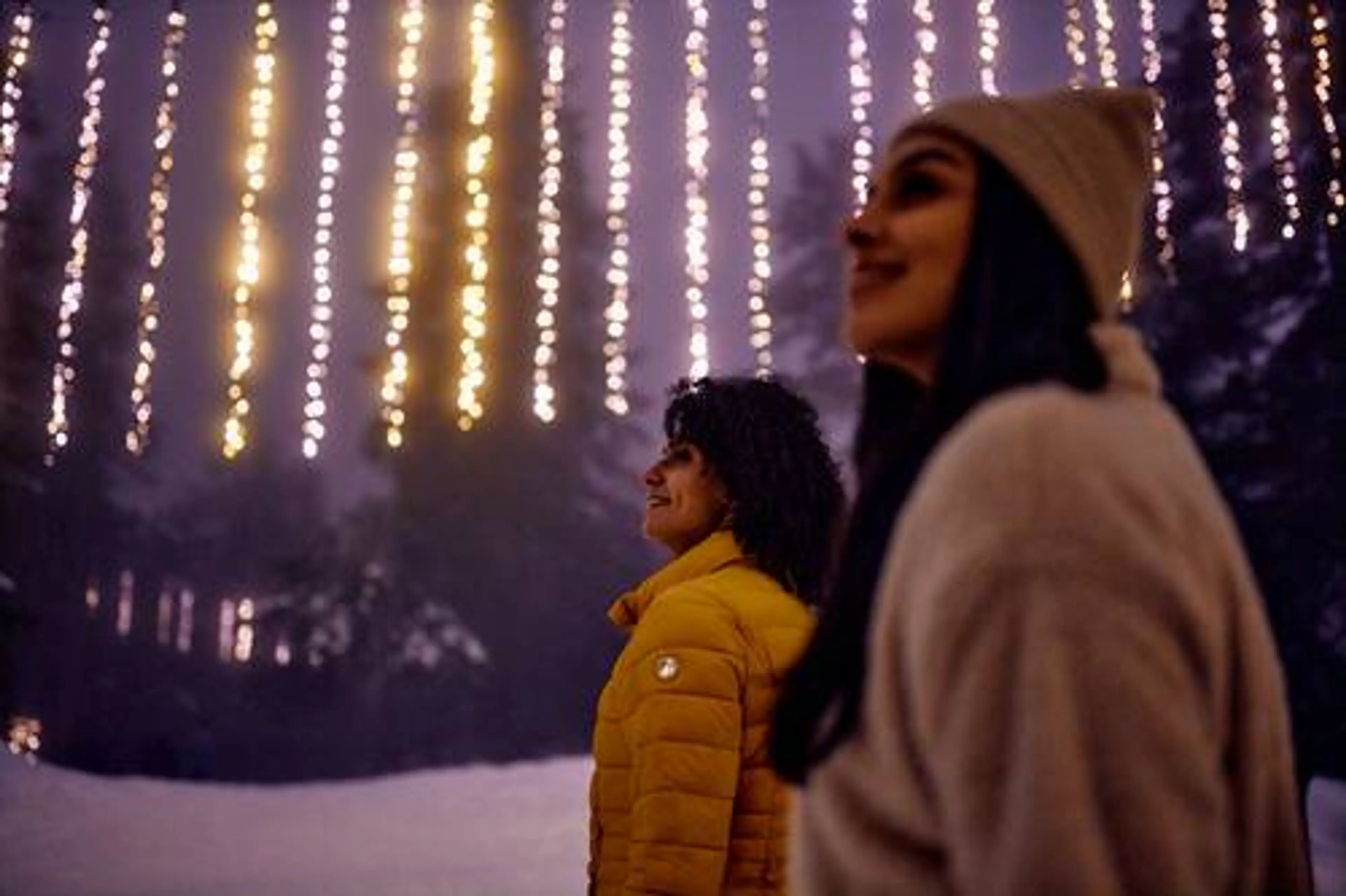 Two visitors standing in awe as they walk under the glowing light installations along the Grouse Mountain Light Walk near Vancouver.