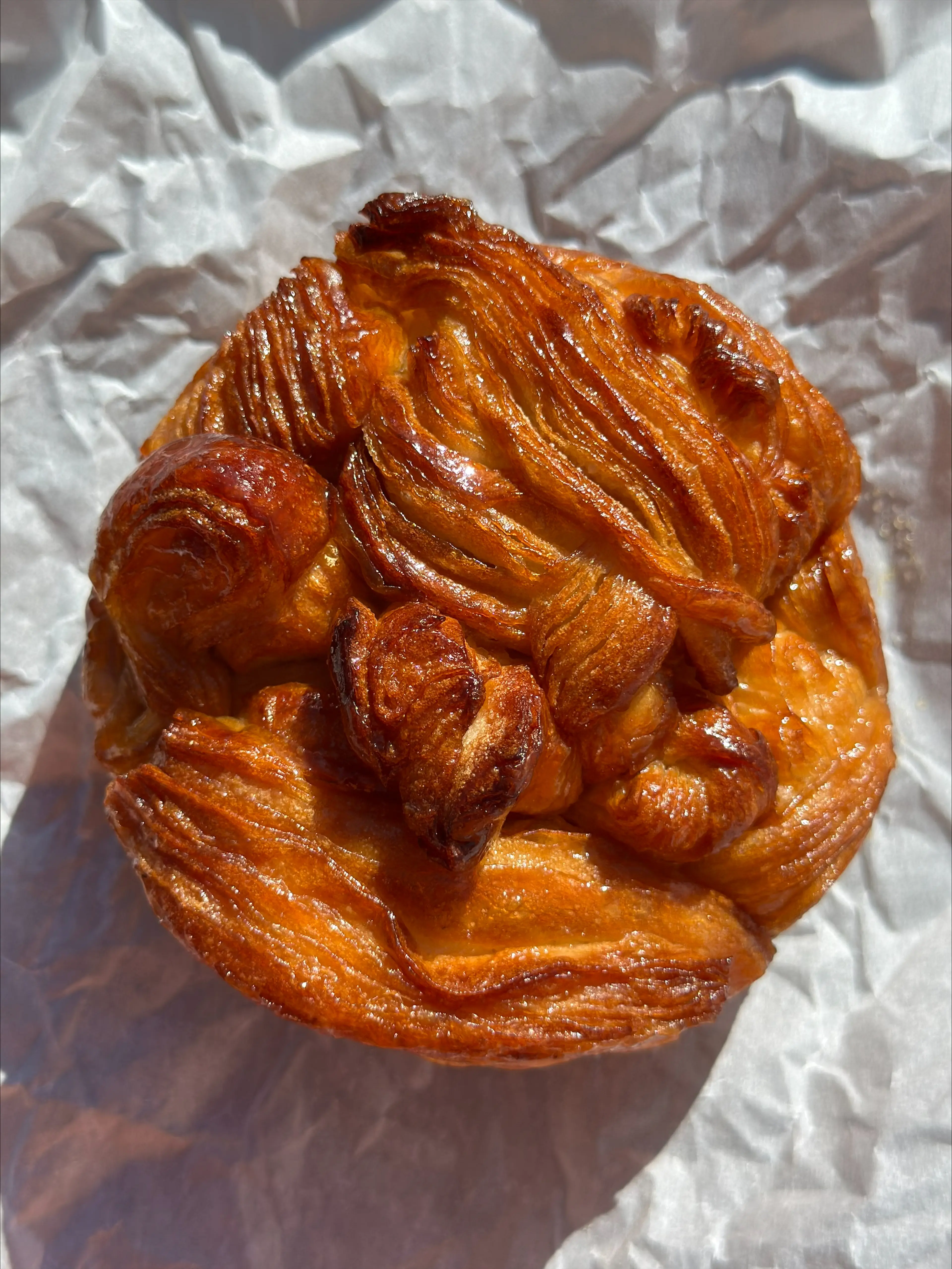 Bonus Bakery's Apple Caramel Monkey Bread Croissant on a crinkled paper wrapper.