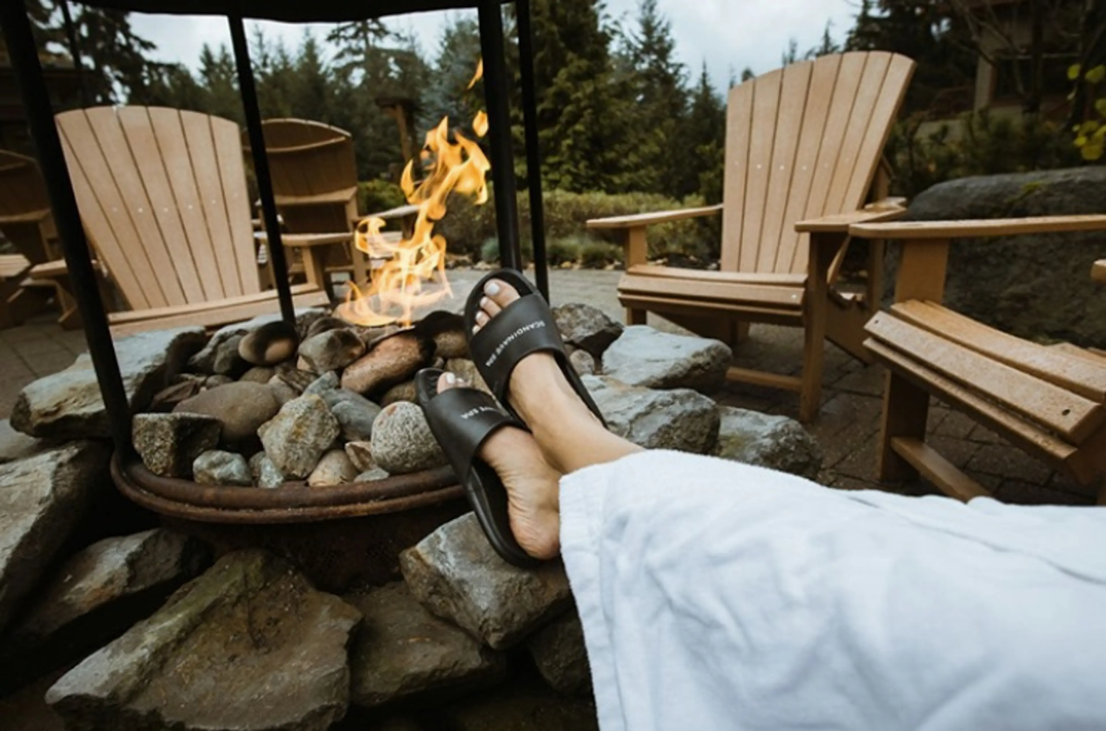 Person relaxing by a firepit at Scandinave Spa in Whistler. Spa retreats Vancouver. 