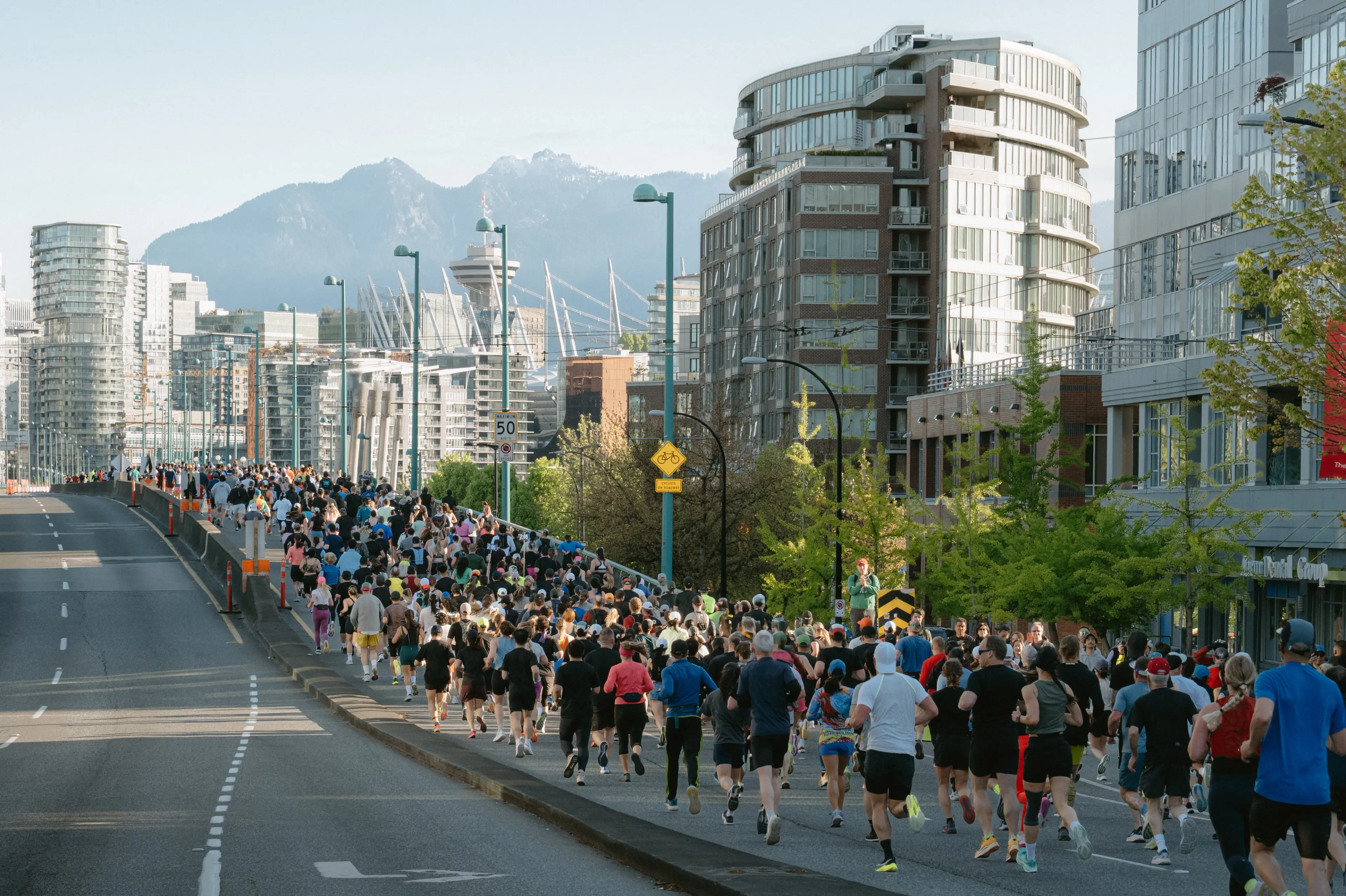 Runners with mountains and downtown in the background at the BMO Vancouver Marathon.