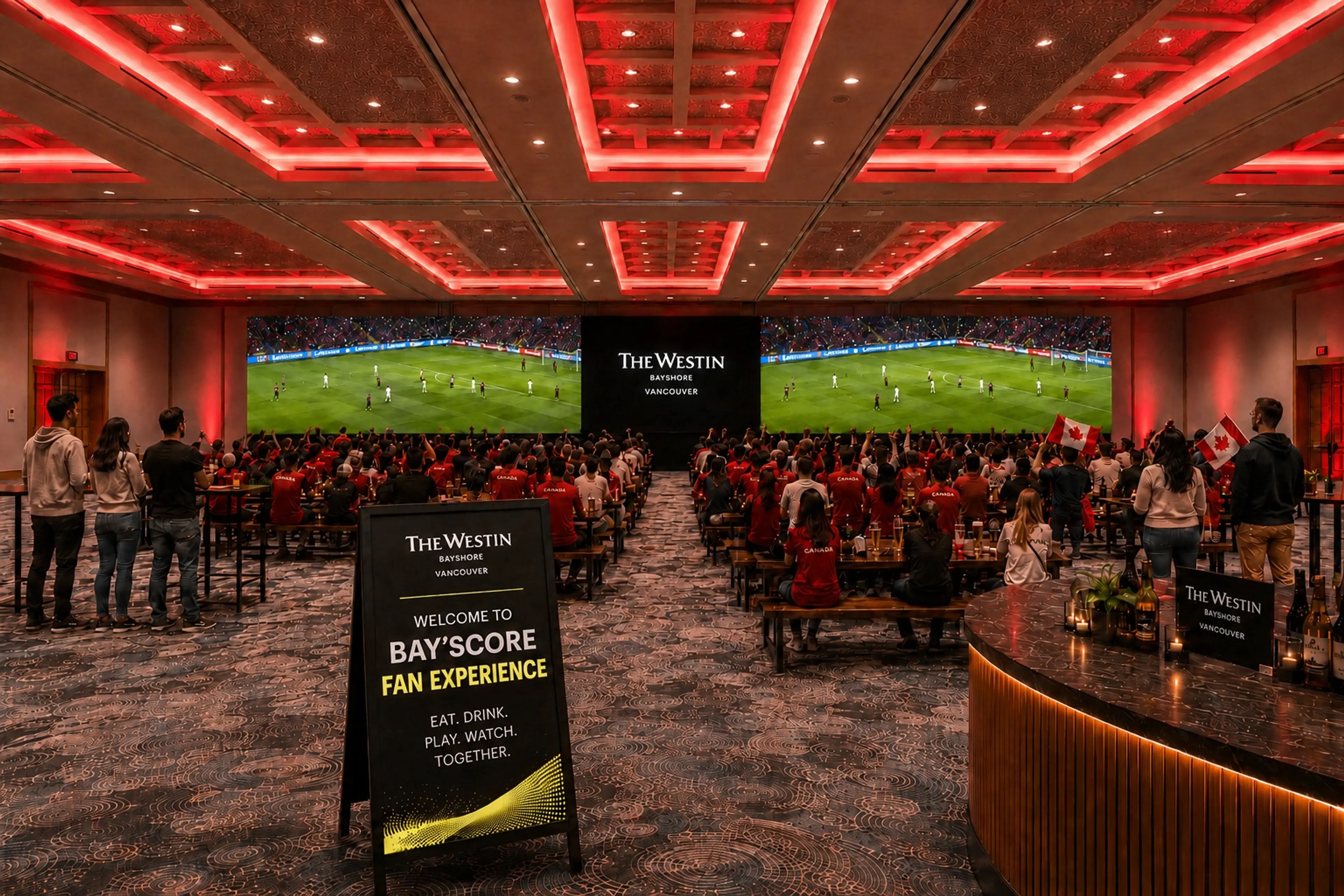 Large group of people watching a soccer match on two big screens in a room with red ceiling lights, some holding Canadian flags.