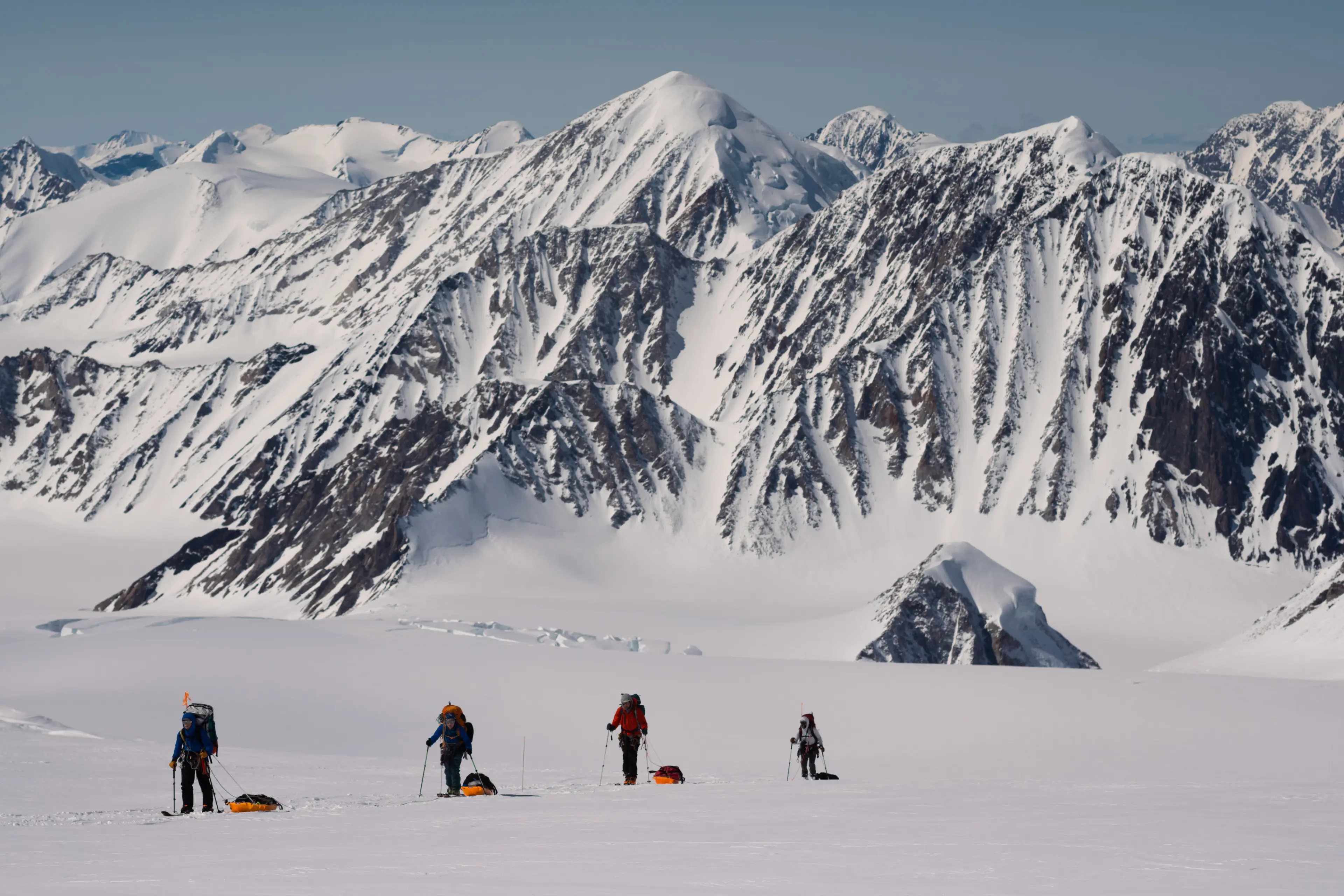 Still image from the film For Winter showing members of an expedition team skiing in front of snow covered mountains