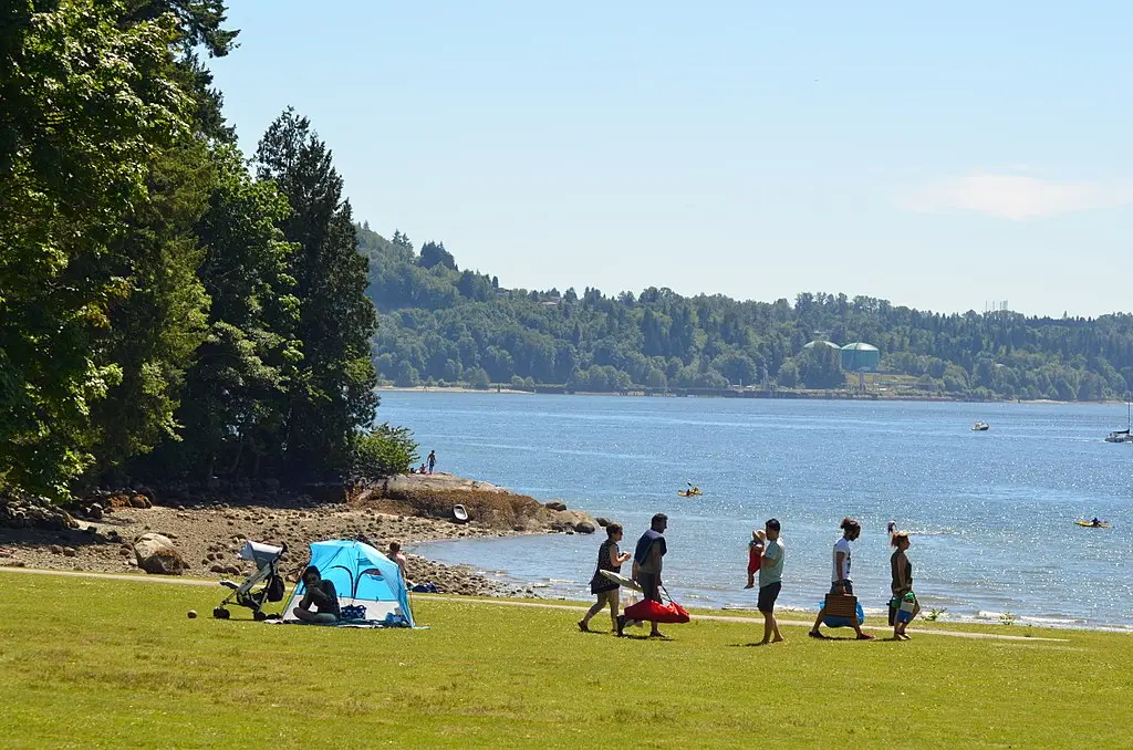 People set up a picnic on the grass near the beach at Belcarra Regional Park