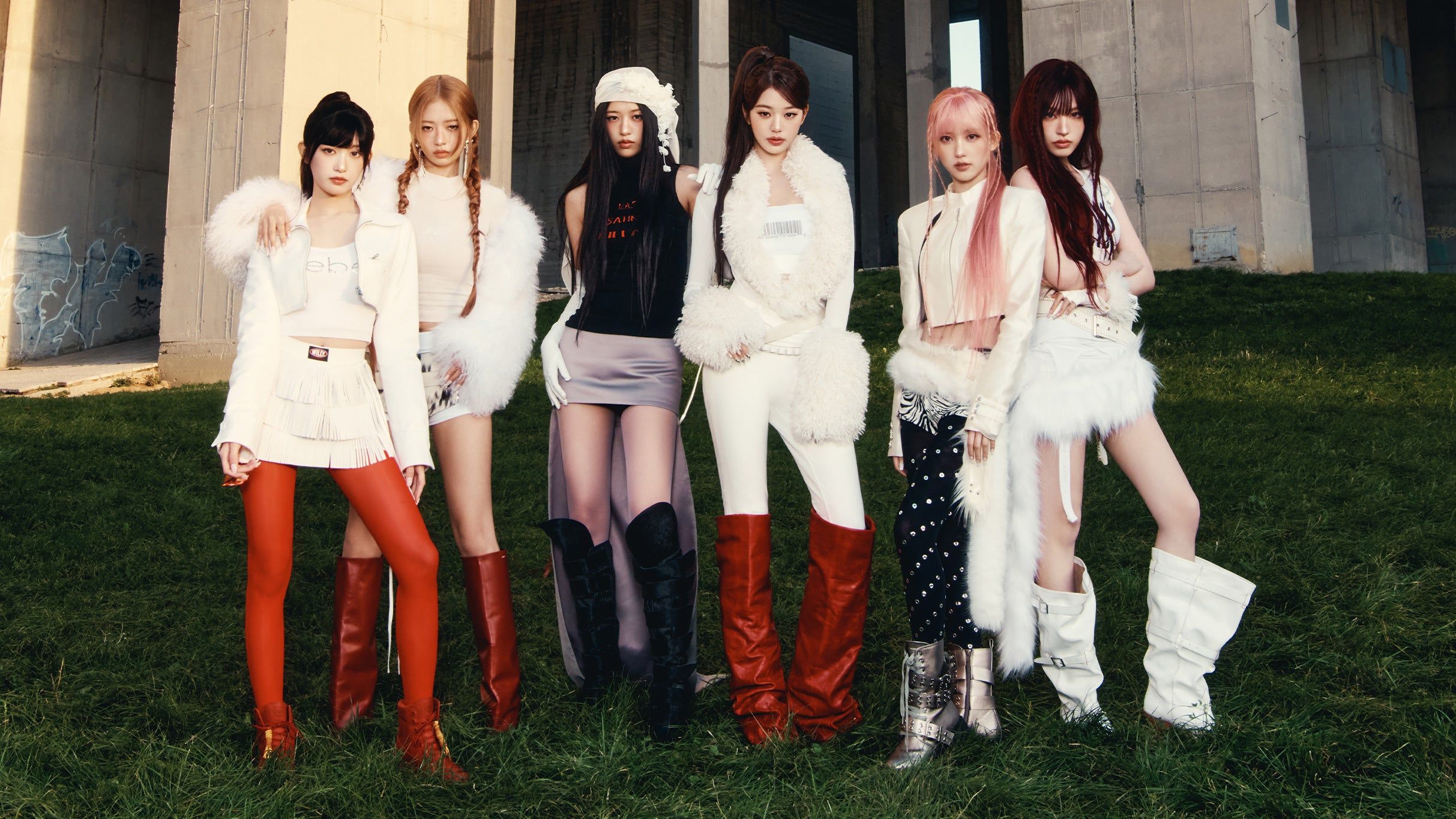Six people standing on grass in front of a concrete structure, wearing stylish white and red outfits with boots.