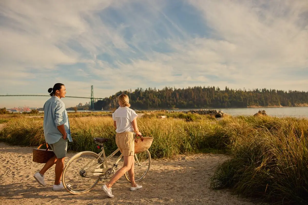 A couple looks for a picnic spot on the beach at Ambleside Park.