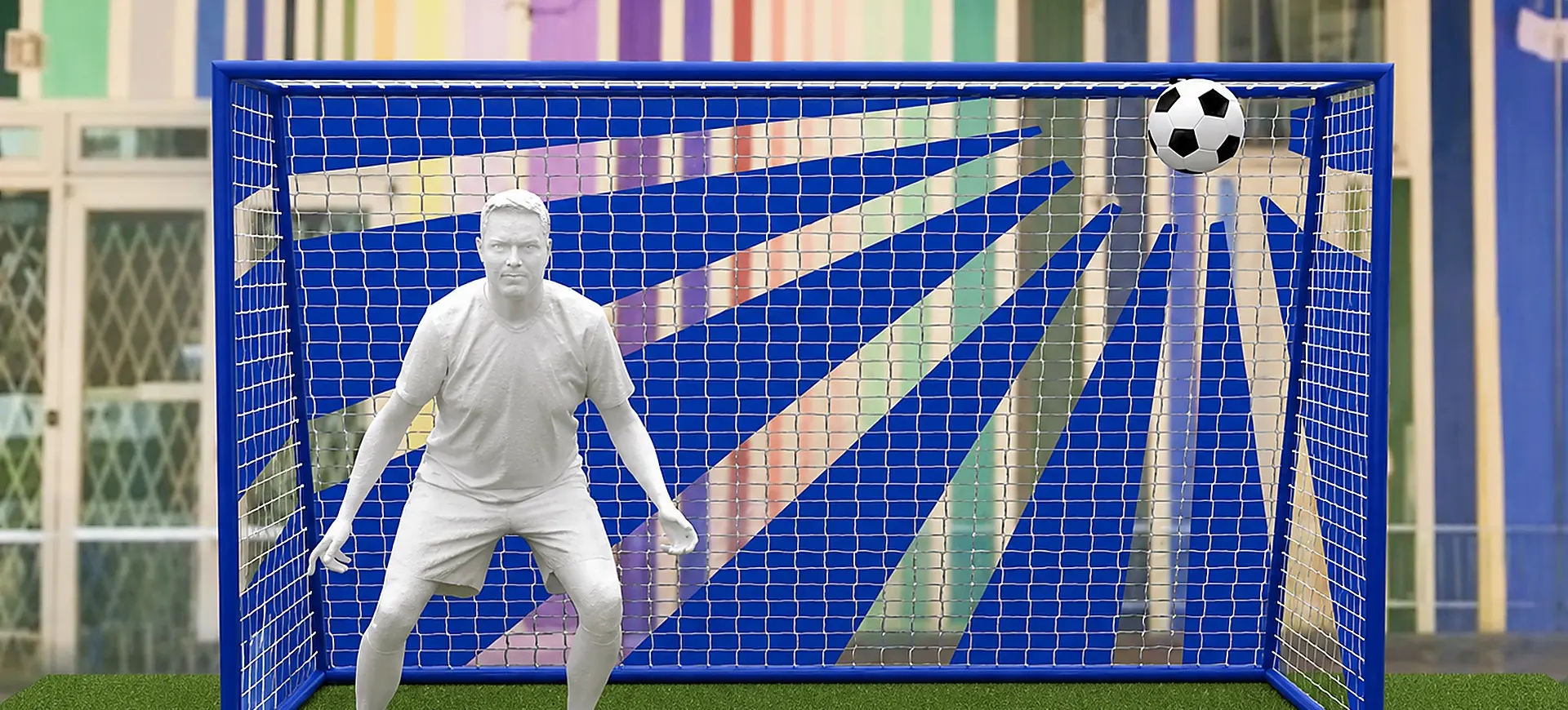 Person in a ready stance inside a blue soccer goal with a soccer ball hitting the top right corner of the net.
