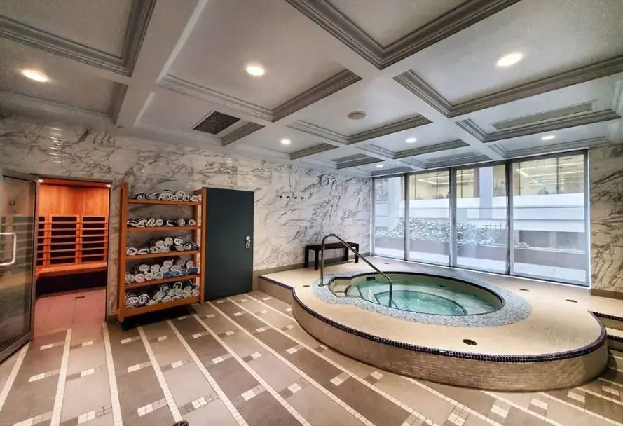 Indoor spa area with a round hot tub, towel rack, sauna room, and large windows.