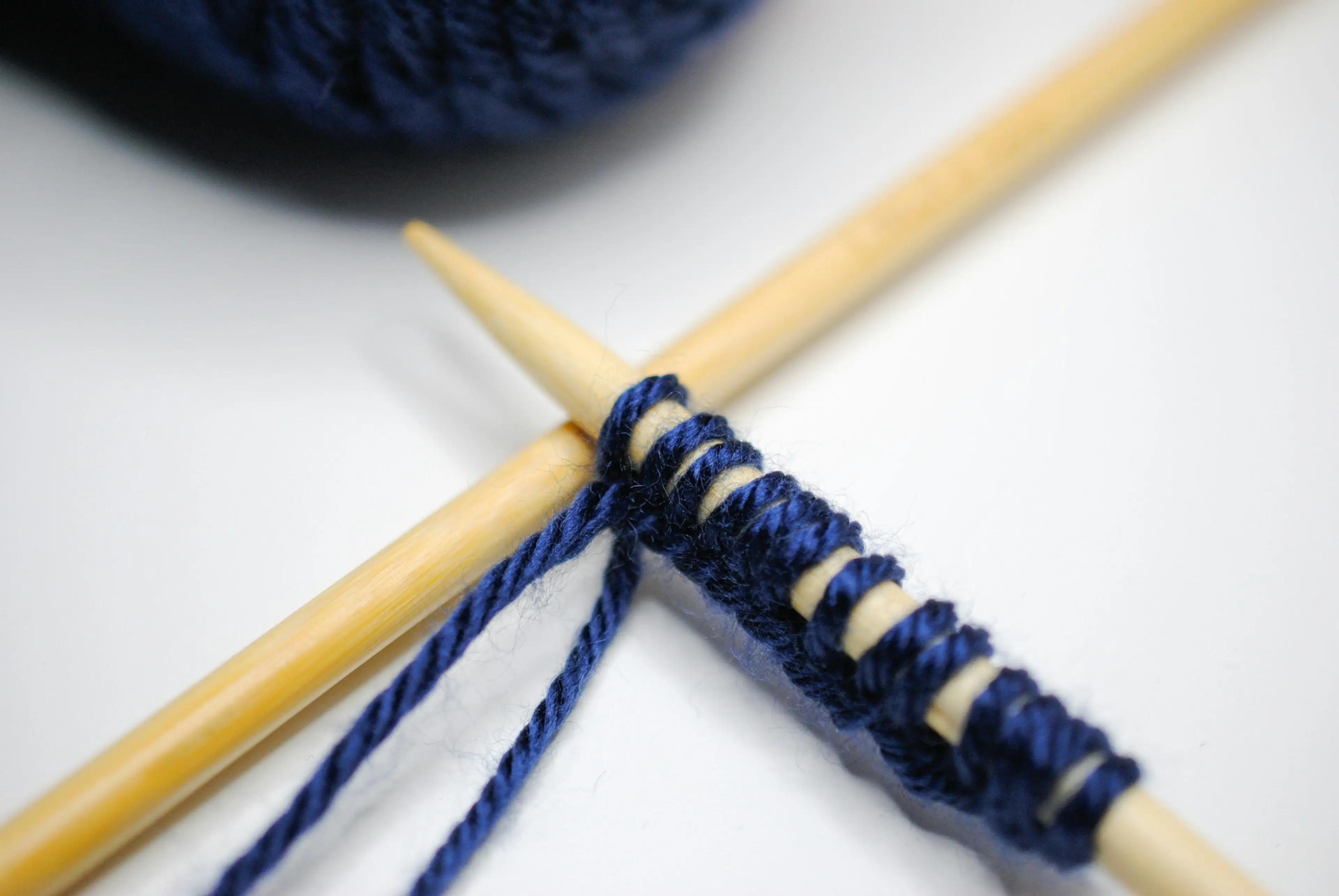 Close up of a pair of knitting needles with blue yarn
