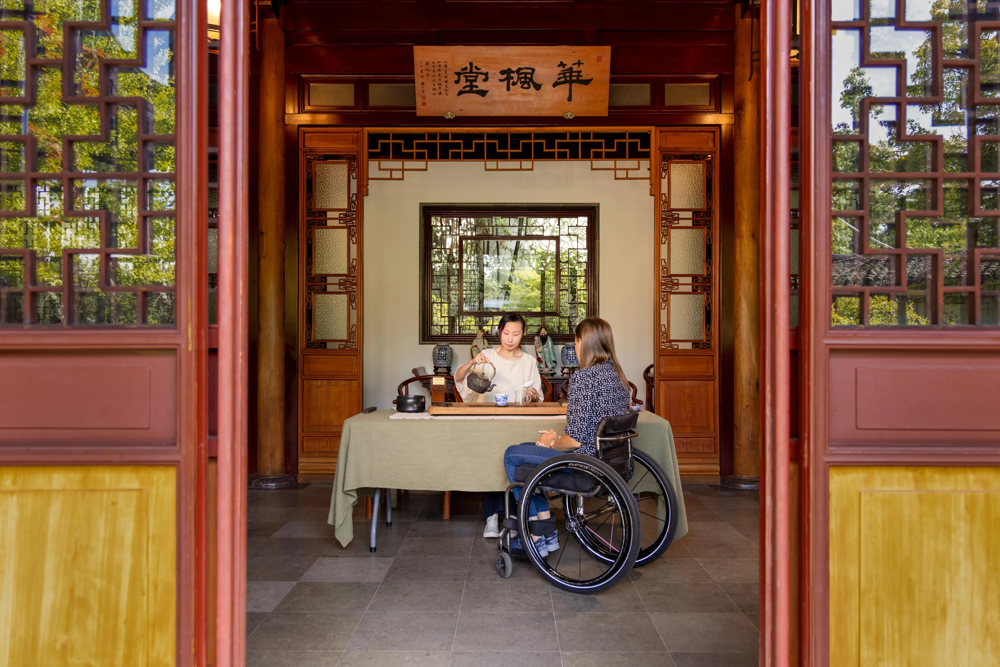 Framed by a doorway, a person pours tea during a tea ceremony at Dr. Sun Yat-Sen Classical Chinese Garden