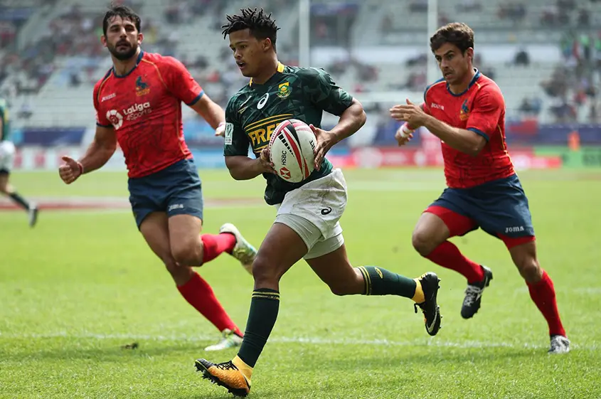 Three rugby players running on the field