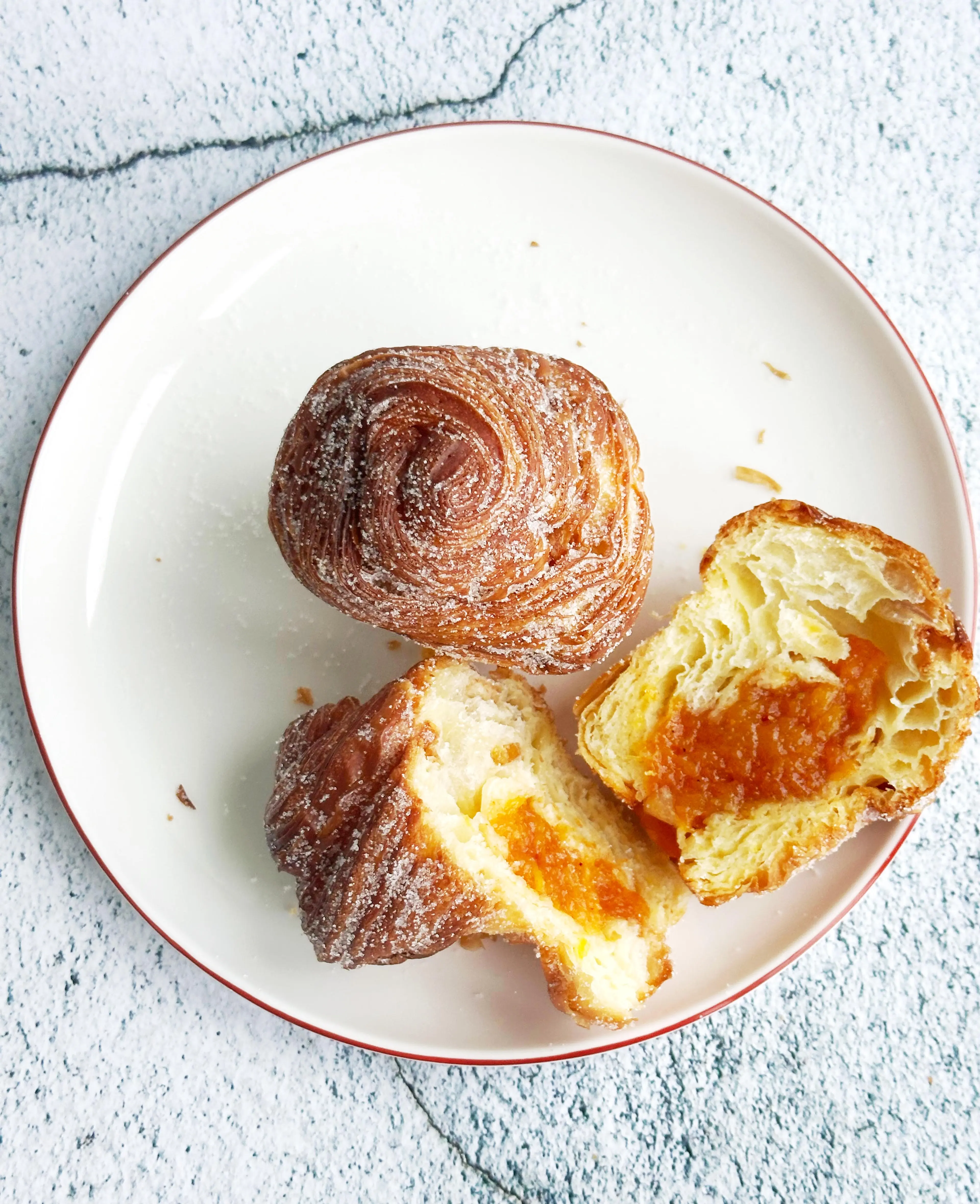 Two of Elaichi Patisserie's Sweet and Spicy Mango Cruffin on a plate, with one cut in half.