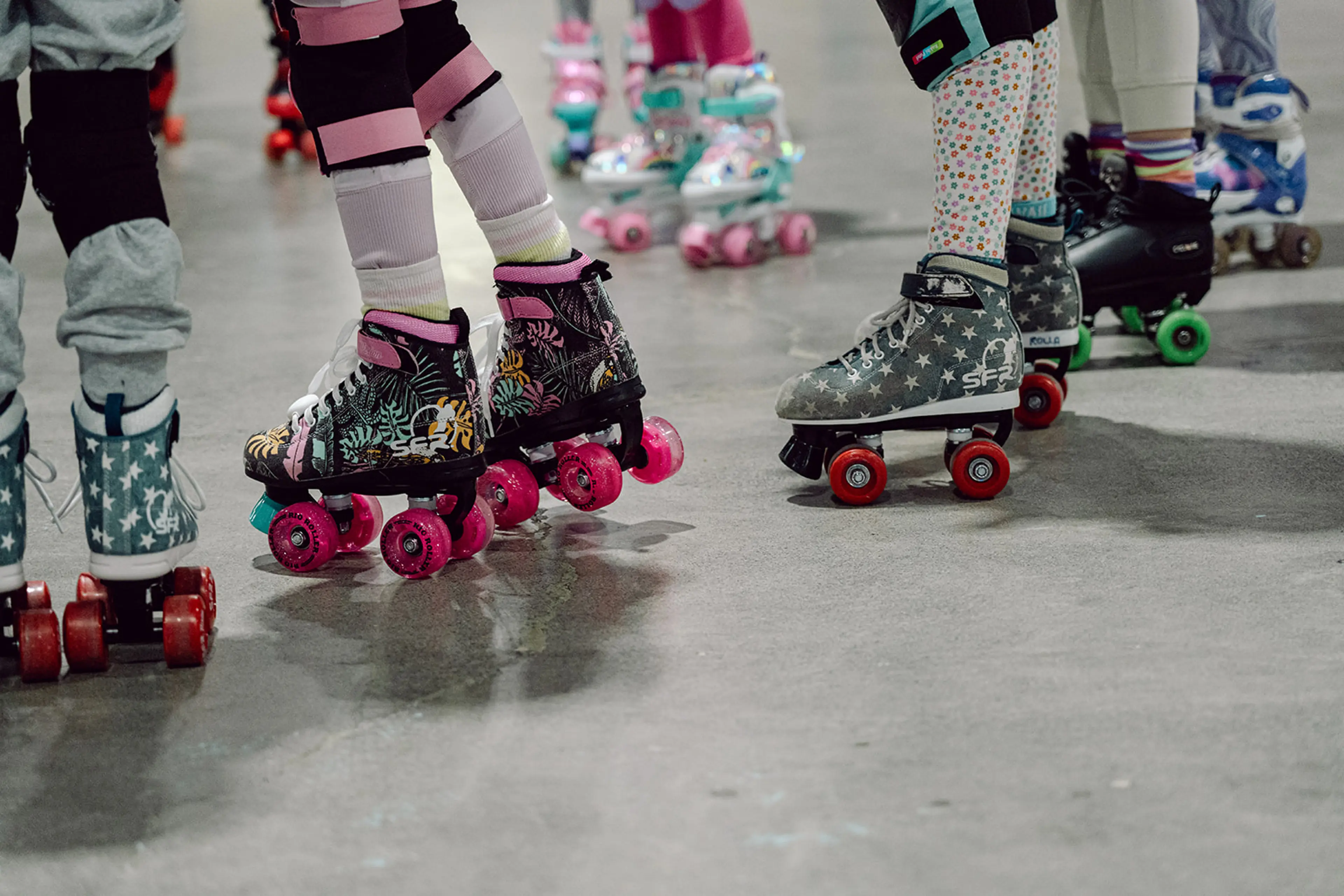 Close up of brightly coloured and patterned roller skates on kids feet at Rolla Skate Club in Vancouver. 