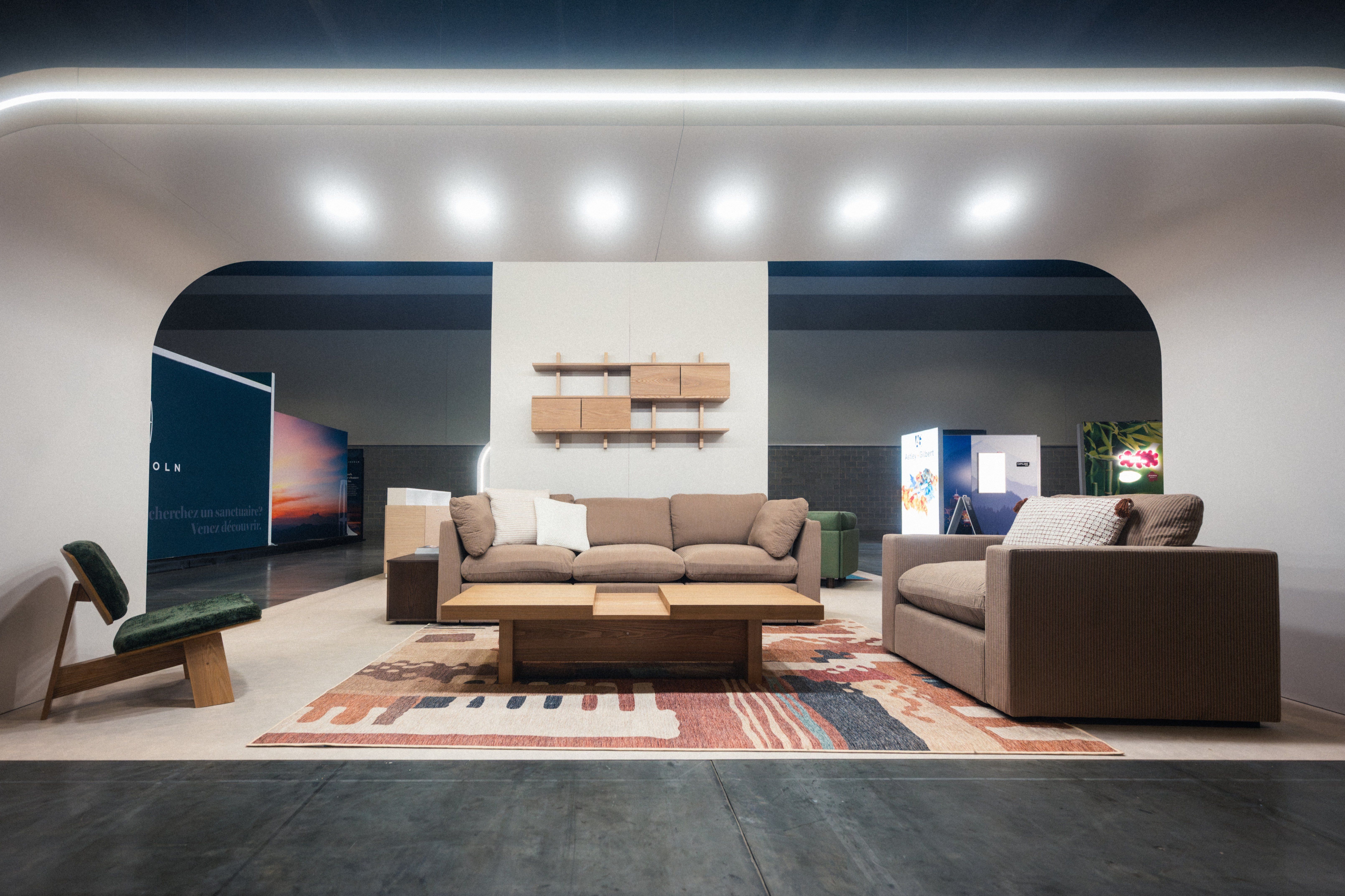 Modern living room setup with beige sofas, a wooden coffee table, a patterned rug, and a green cushioned chair under curved ceiling lights.