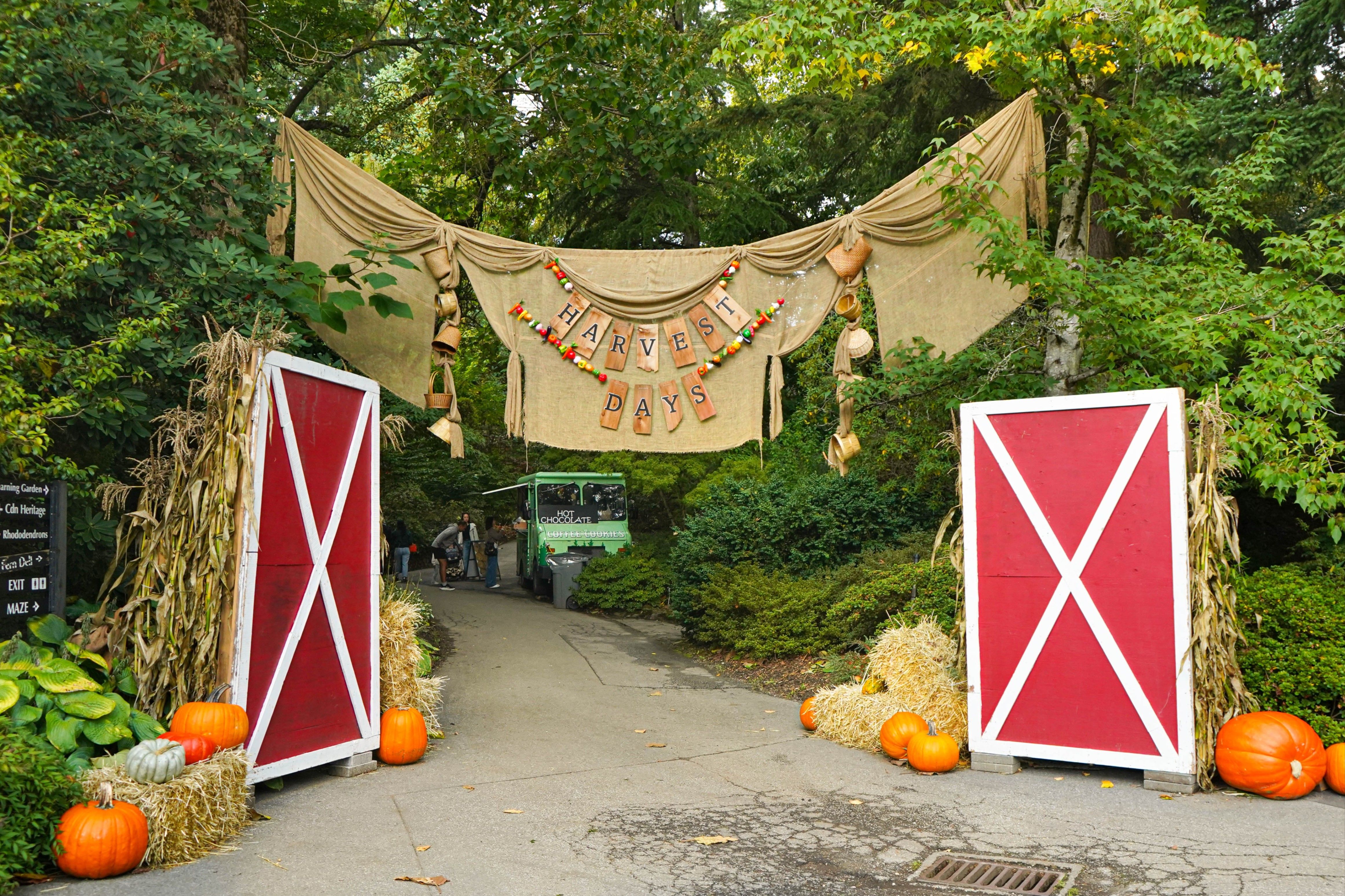 Pathway entrance decorated with red barn doors, hay bales, pumpkins, corn stalks, and a burlap banner reading Harvest Days.