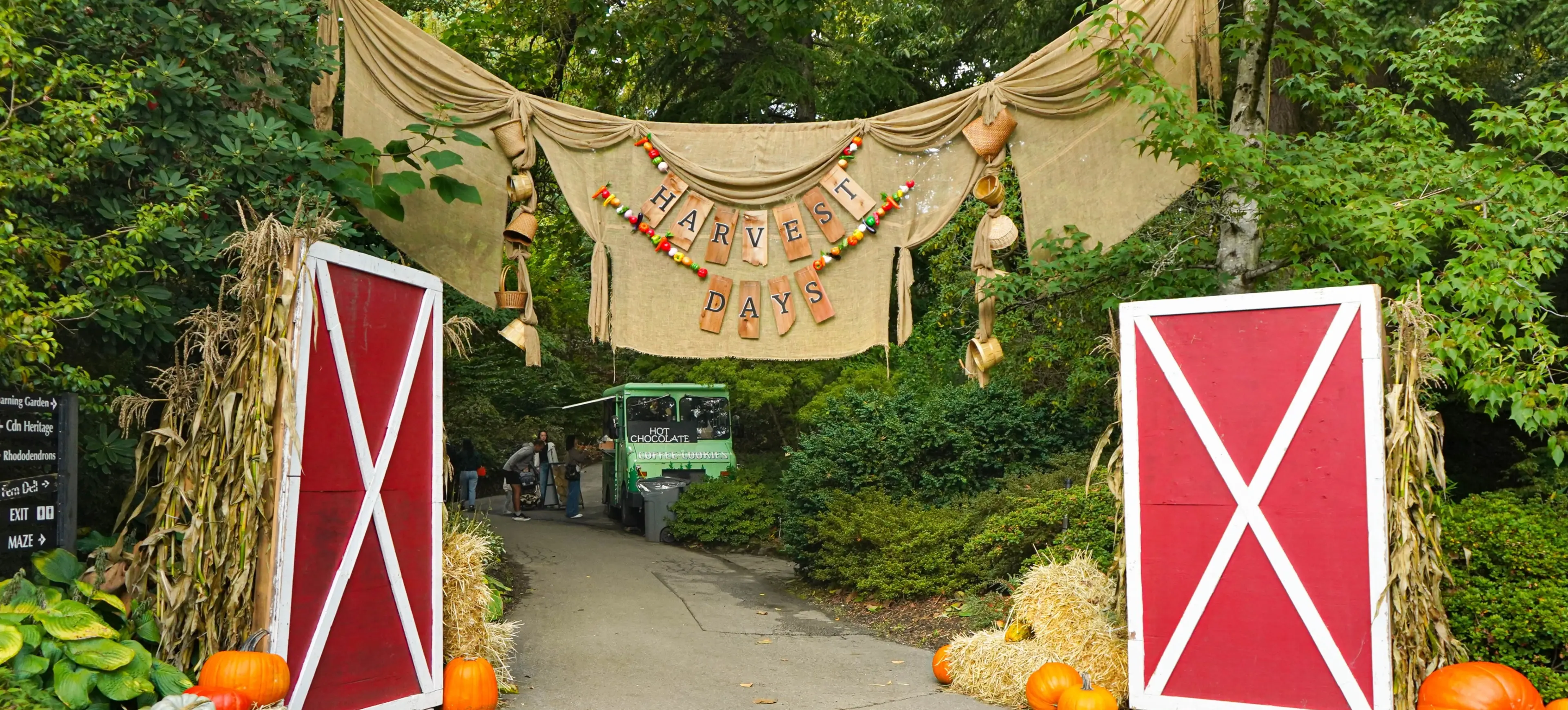 Pathway entrance decorated with red barn doors, hay bales, pumpkins, corn stalks, and a burlap banner reading Harvest Days.