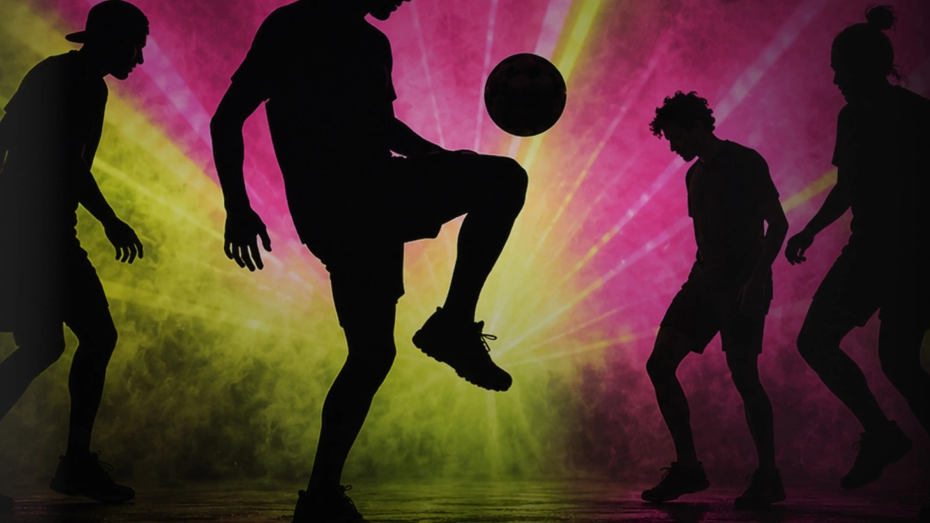 Silhouettes of four people playing soccer with a ball against a colorful pink and yellow radiant background.
