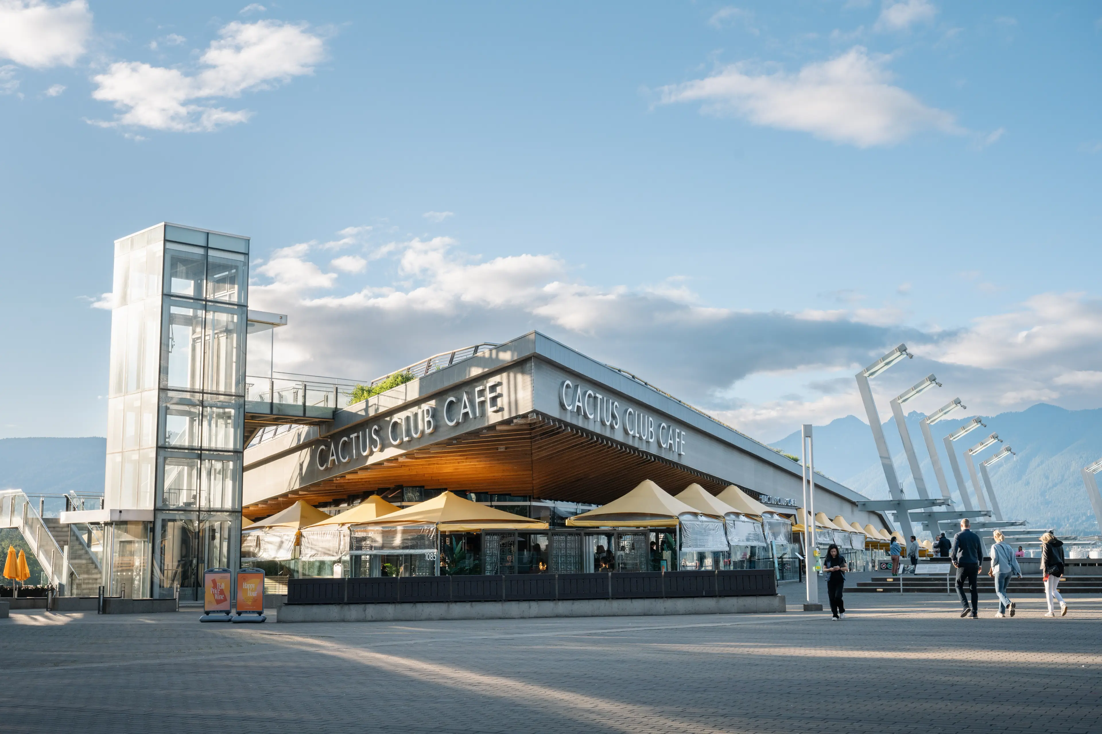 Exterior image of the Cactus Club in Coal Harbour in Vancouver with mountains in the background.