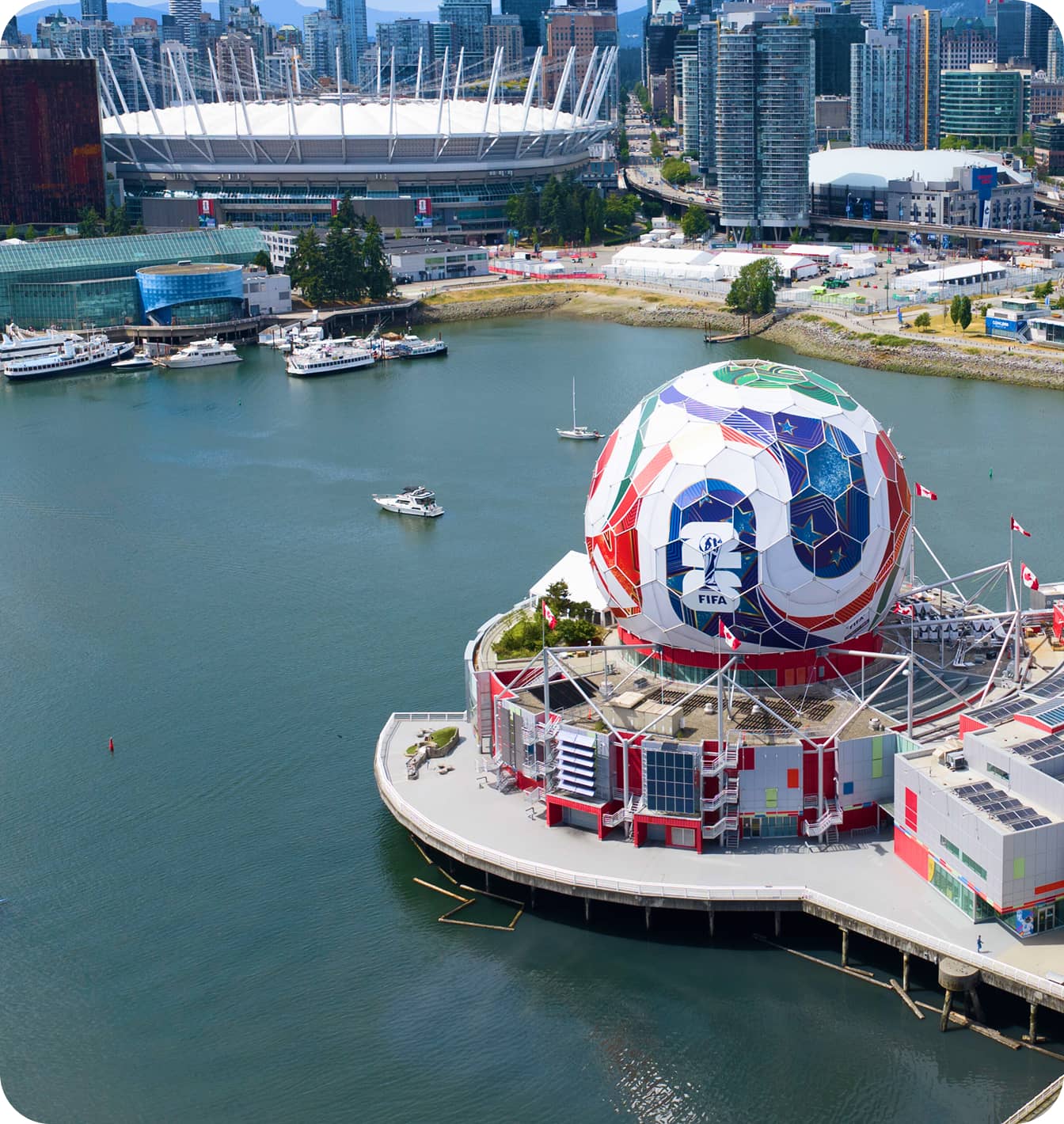 Waterfront cityscape with a large colorful spherical building featuring FIFA 2026 logo and boats on the water.