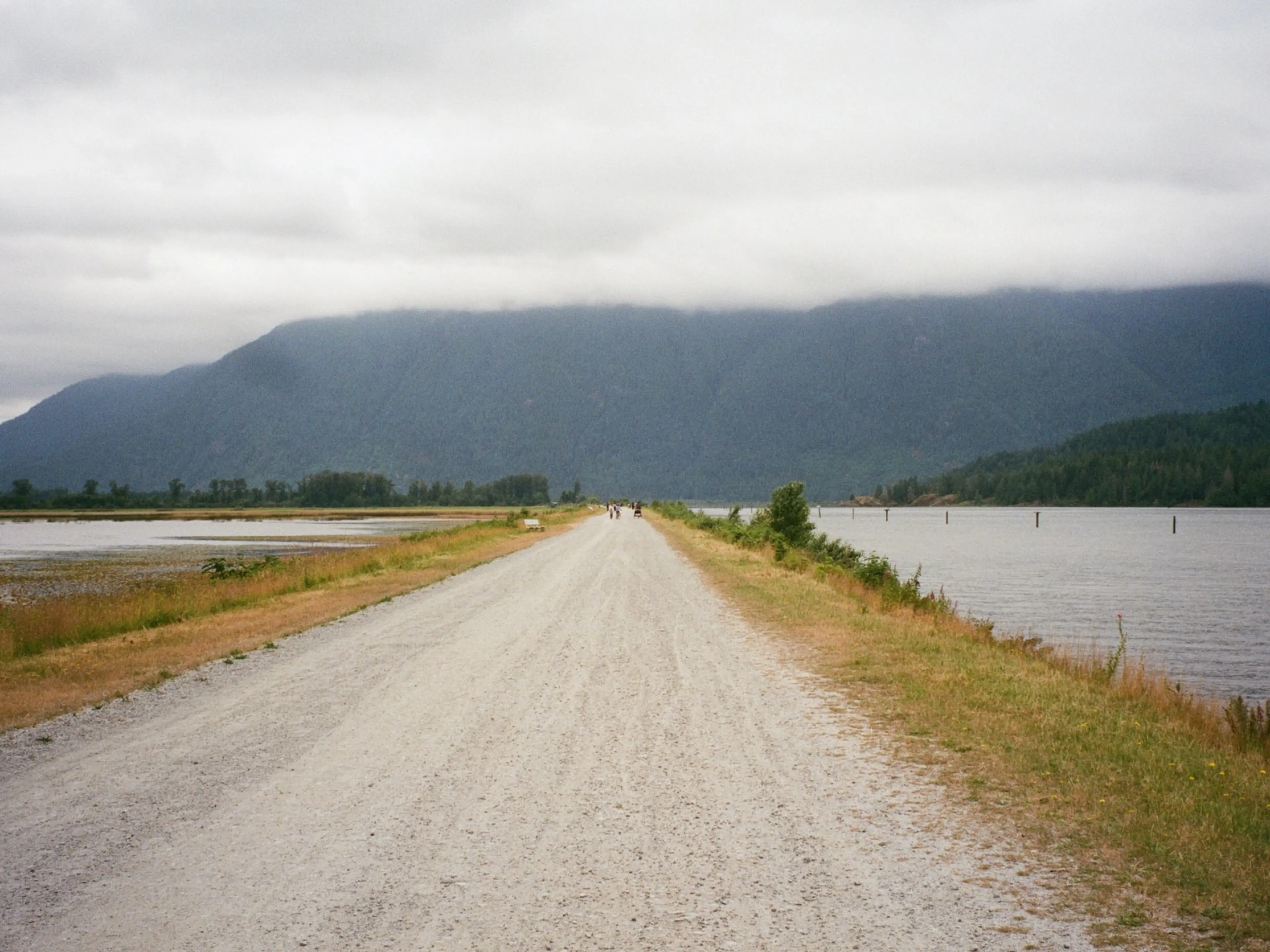 People walk along a dyke at Pitt Lake