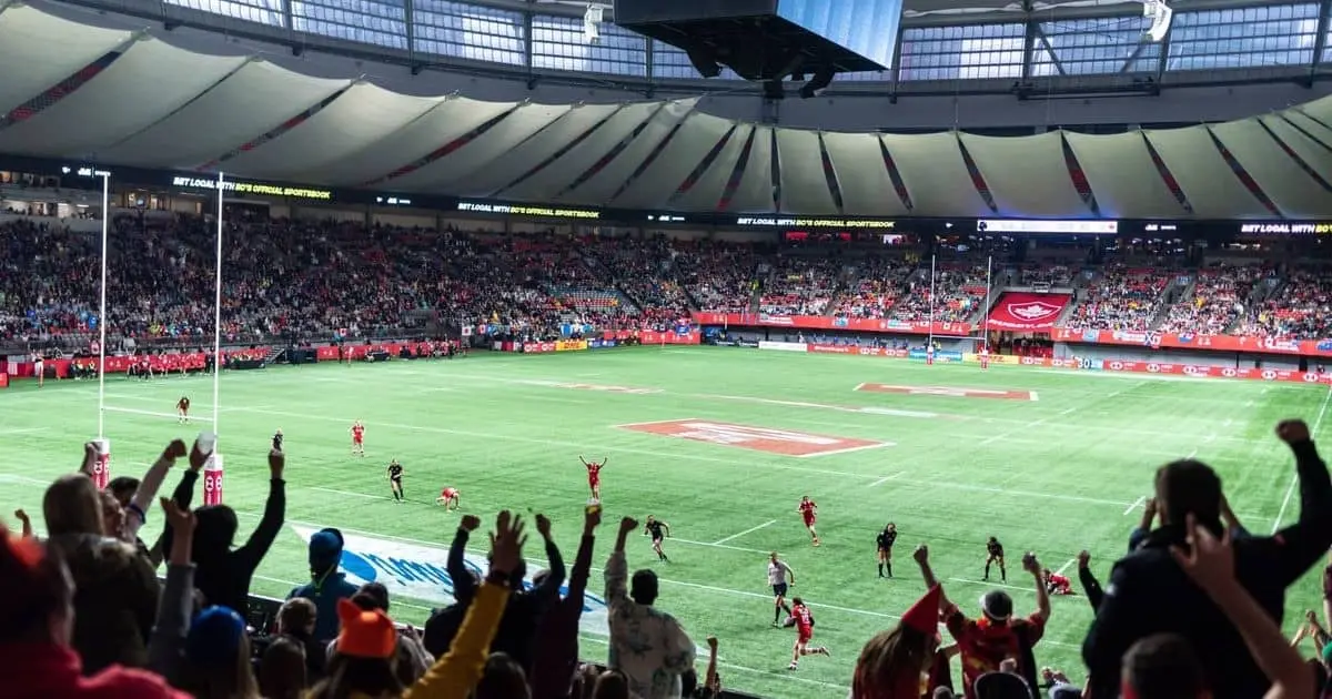 Cheering soccer fans are watching a game being played in an outdoor stadium