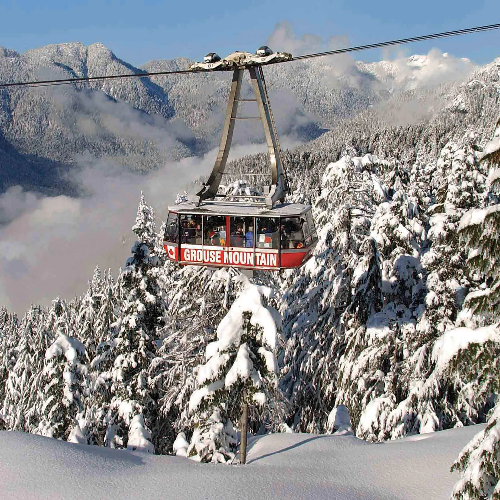 A red Grouse Mountain cable car glides over snow-covered trees, with misty, forested mountains in the background—a quintessential winter highlight for any Vancouver itinerary.