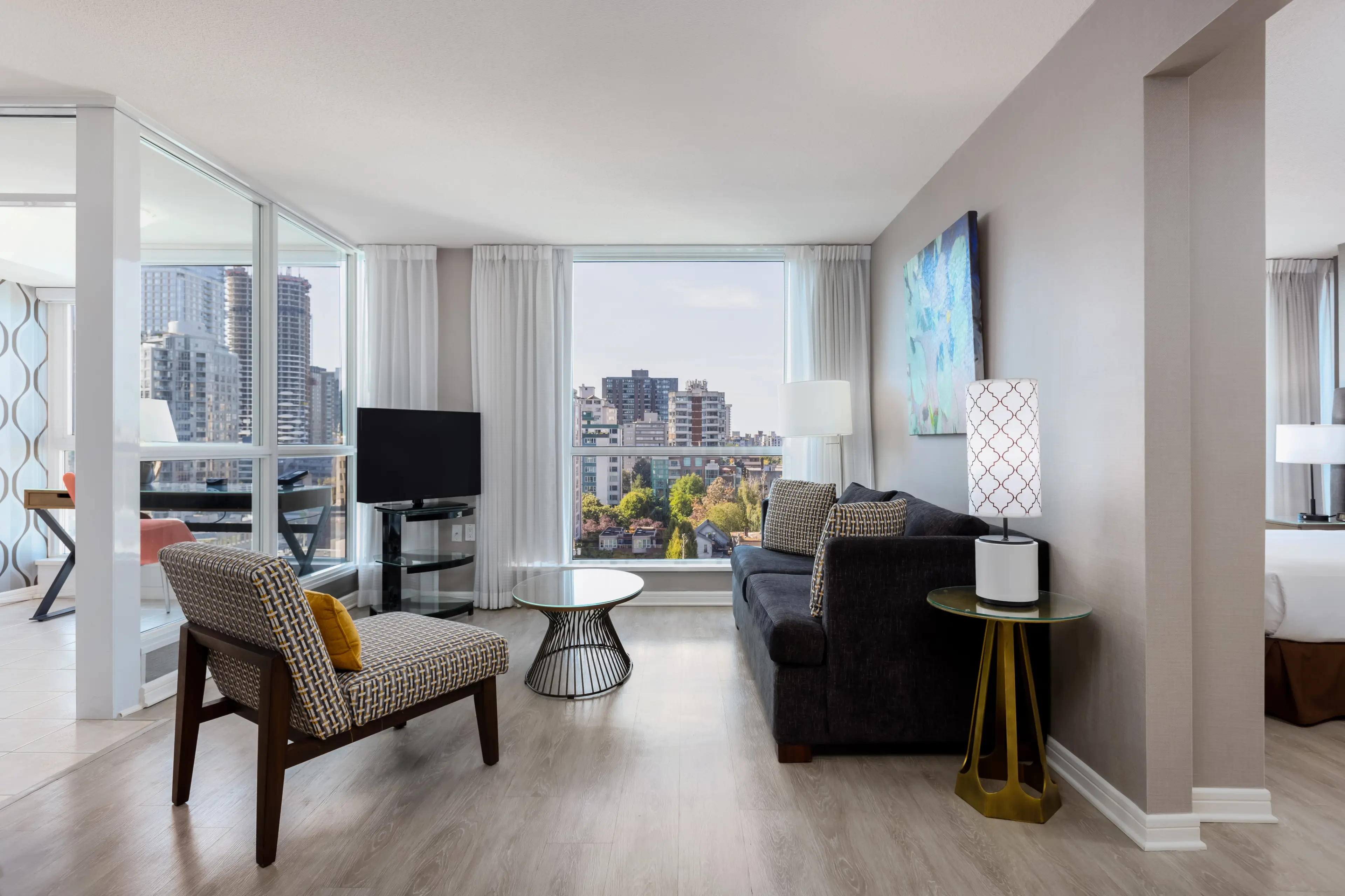 The living area of a one bedroom suite at Carmana Hotel in Vancouver with a city view out the window. 