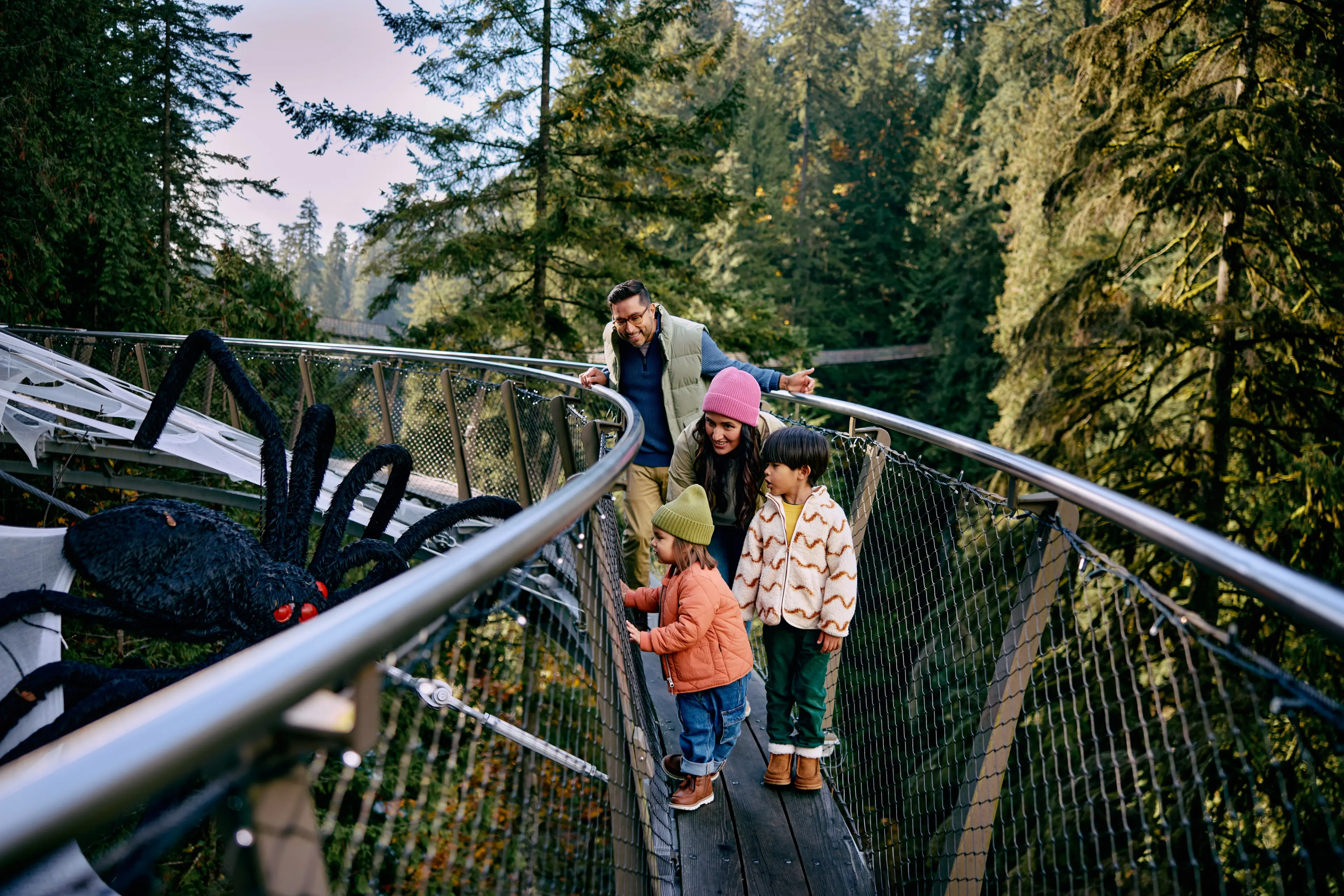 Two parents and two little kids enjoying the spider decoration during the Fright Nights at the Capilano Suspension Bridge Park in North Vancouver.