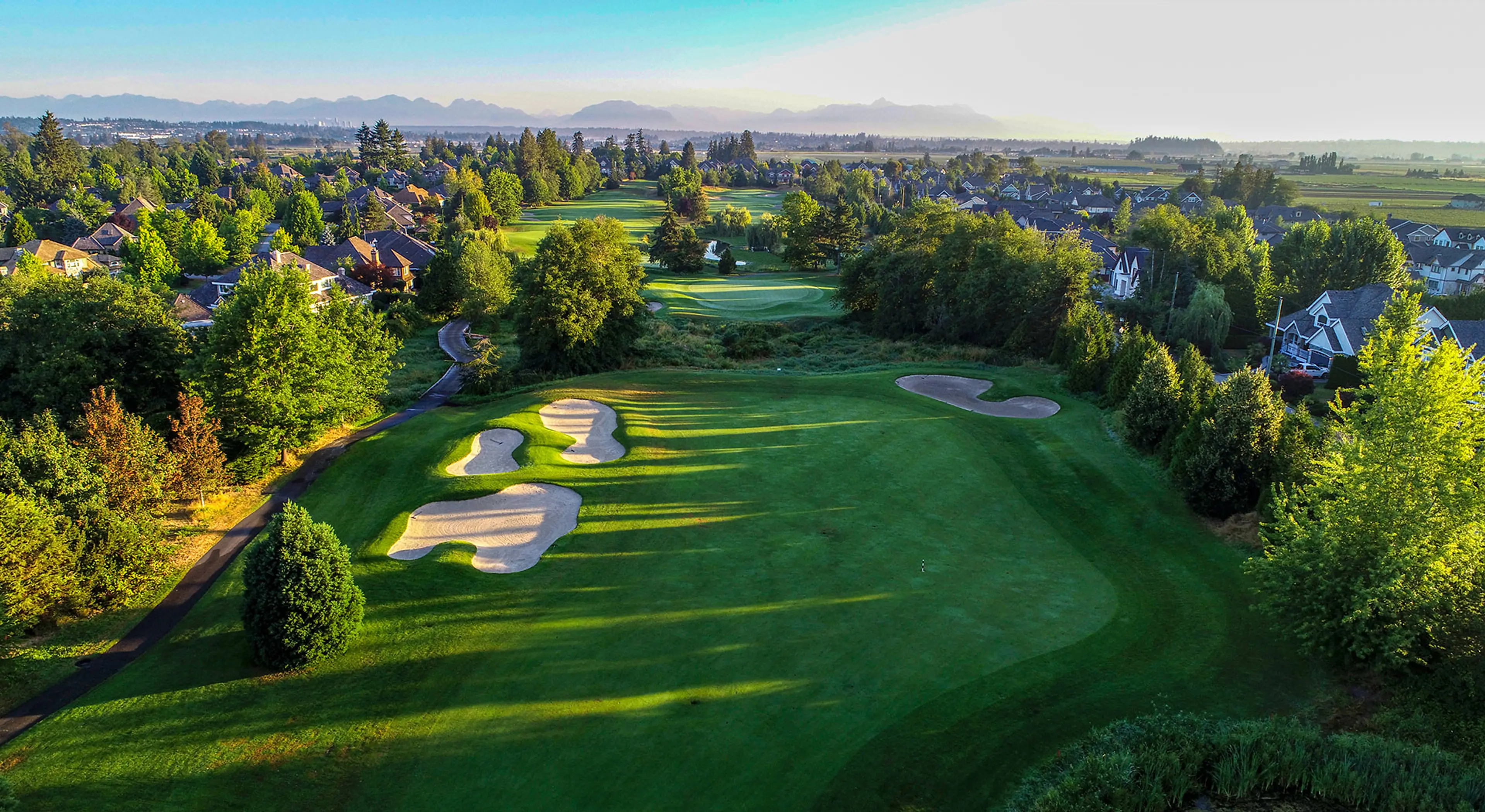 Aerial view of the Morgan Creek Golf Course in Surrey with mountains in the background. 