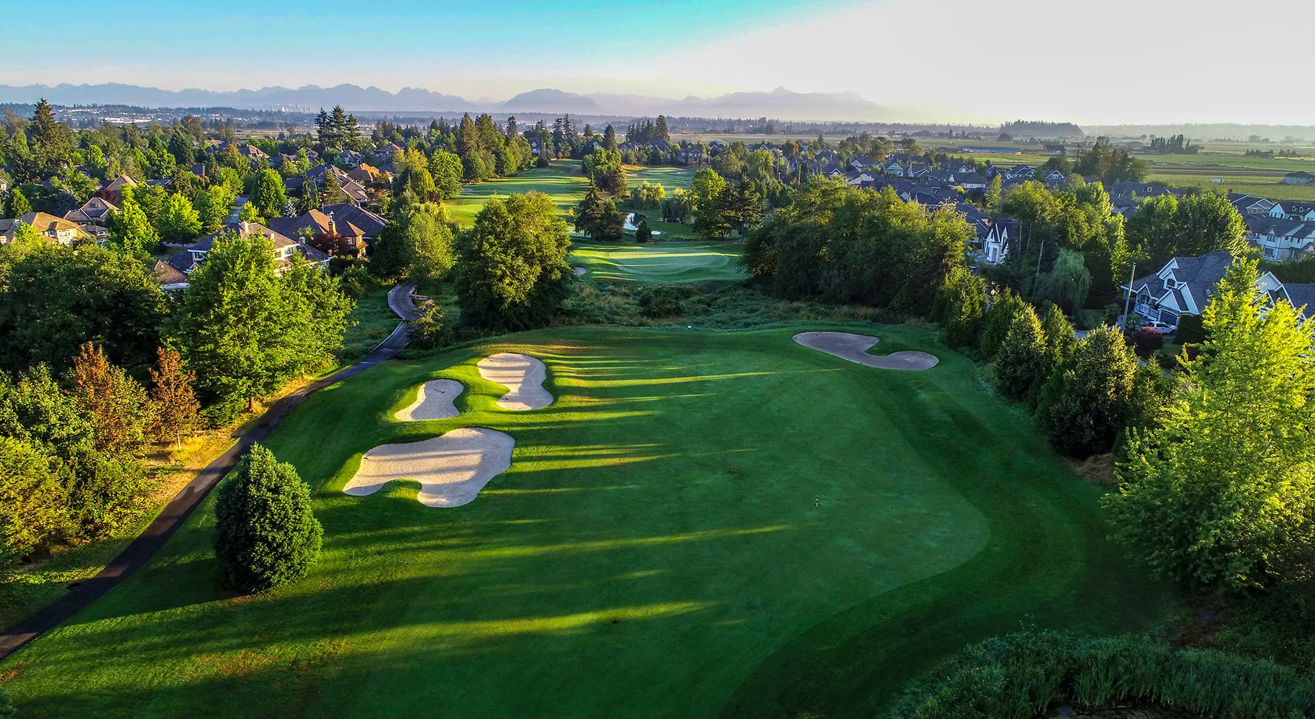 Aerial view of the Morgan Creek Golf Course in Surrey with mountains in the background.