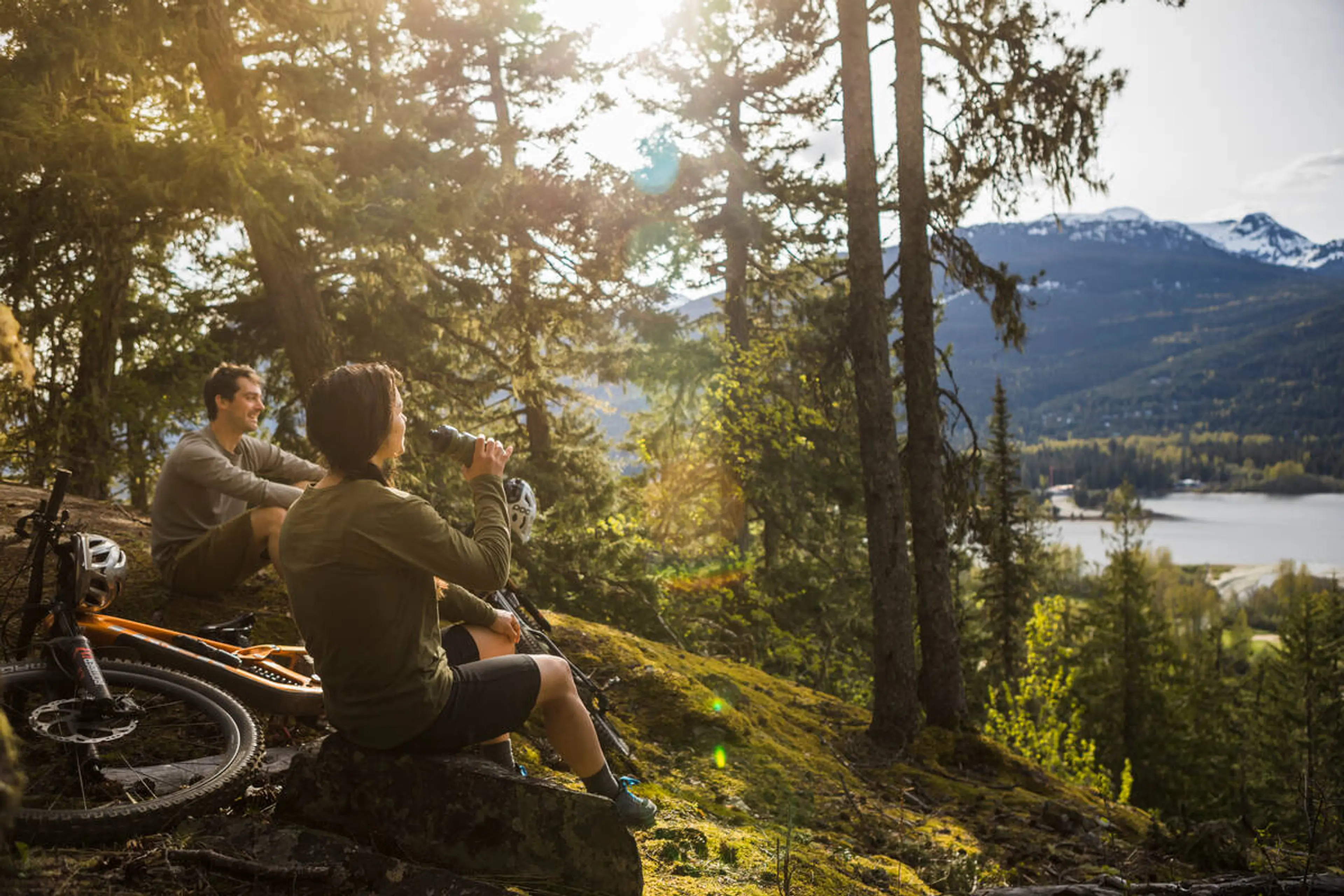 Two mountain bikers take a break on a trail in Whistler. 